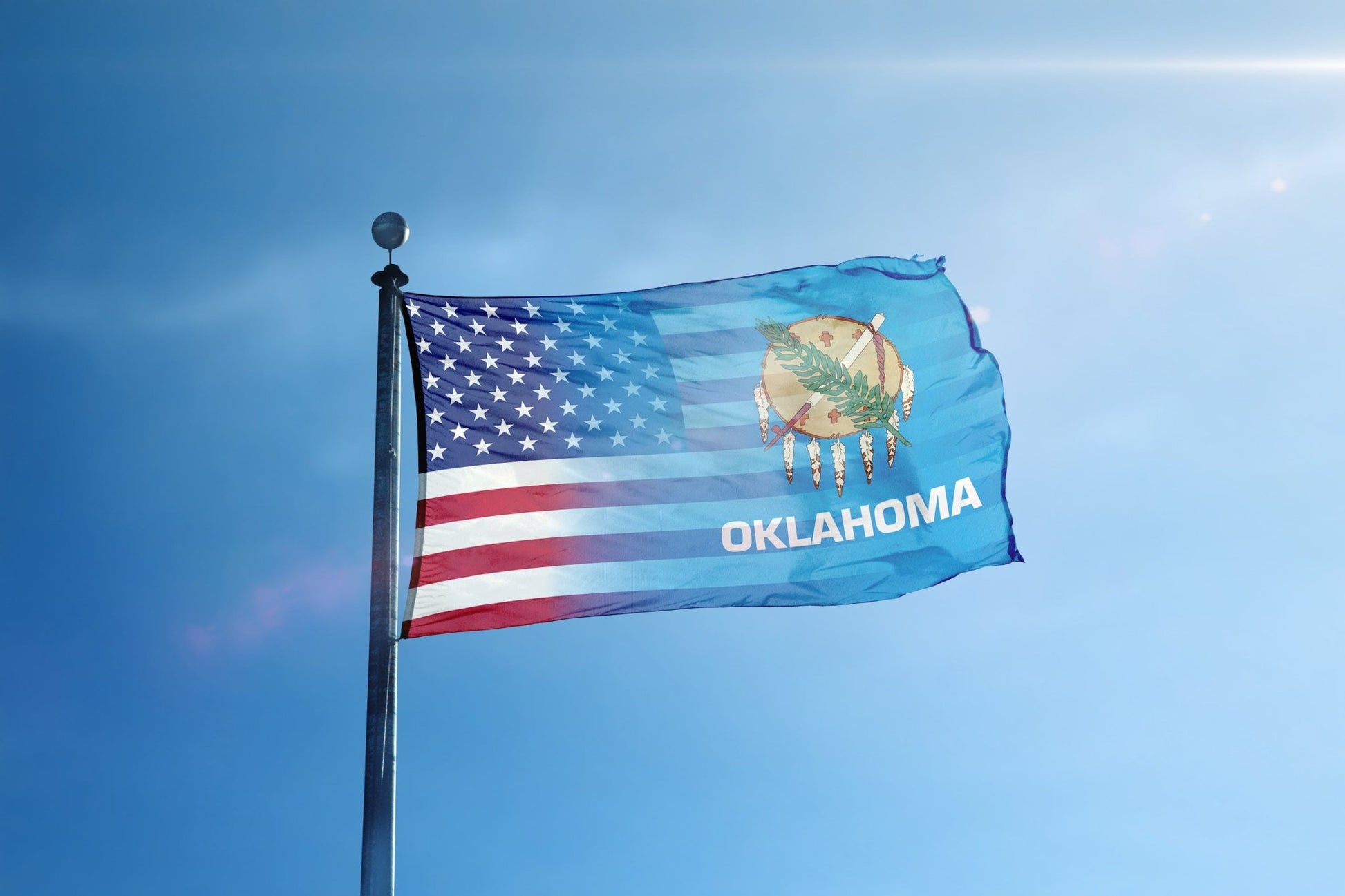 the flag of the state of oklahoma flies high in the blue sky