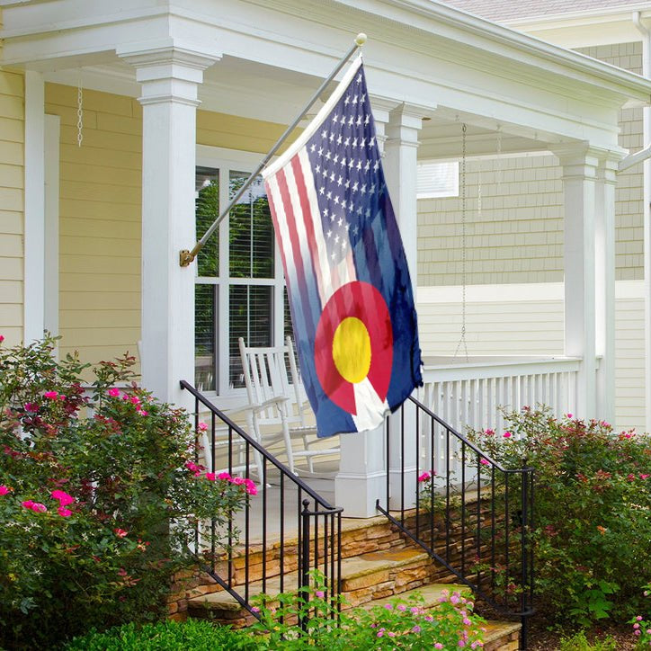 an american and colorado flag blended together on a flagpole in front of a house