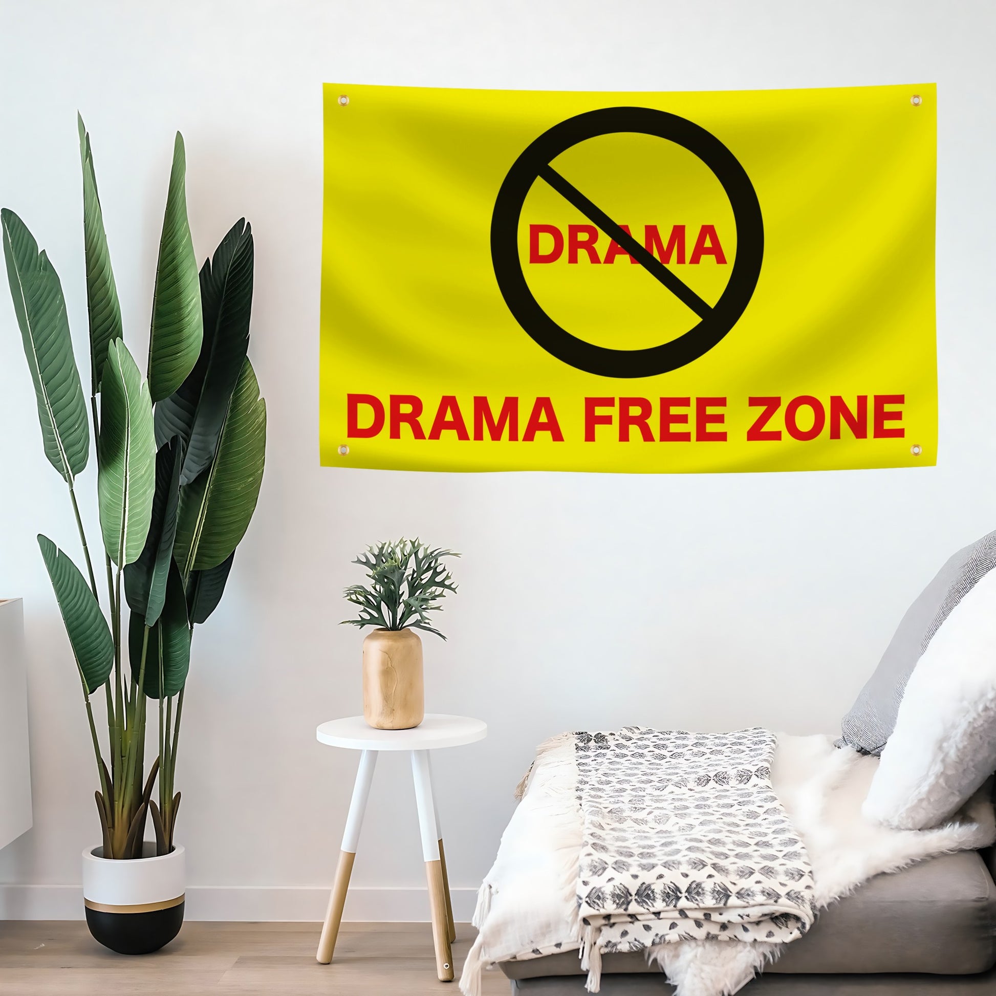 Yellow 'Drama Free Zone' flag banner on a wall above a sofa with decorative plants.