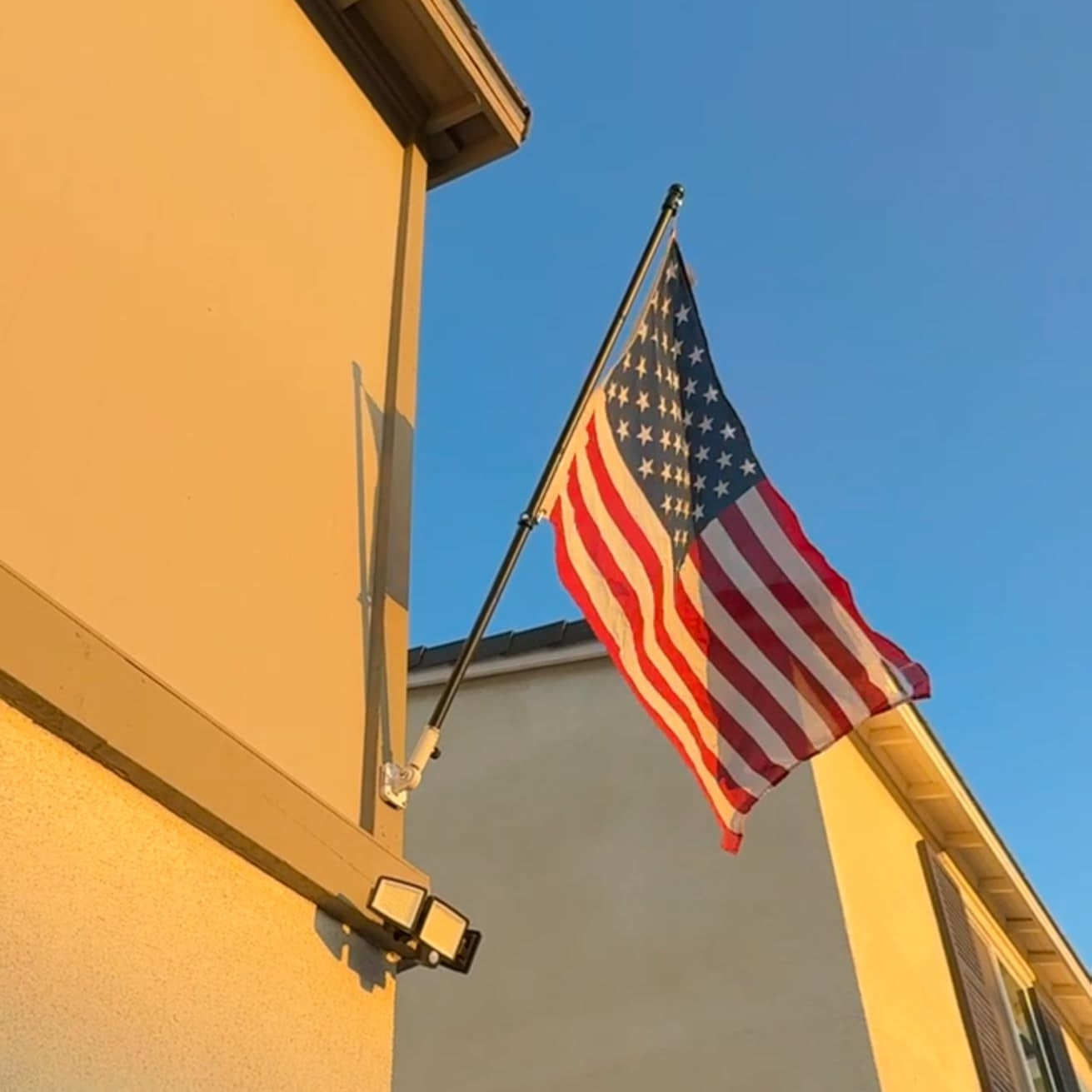 American flag waving on a flagpole against a clear blue sky.
