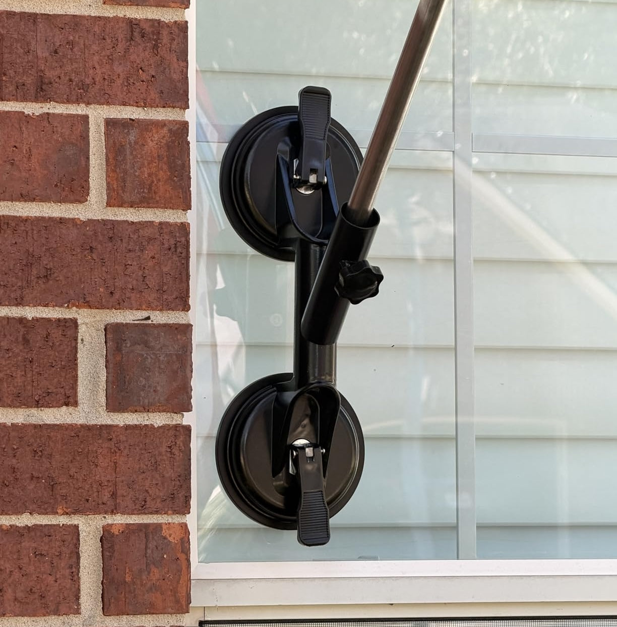 Close-up of suction cup flag pole mount on window showing secure attachment and adjustable pole holder