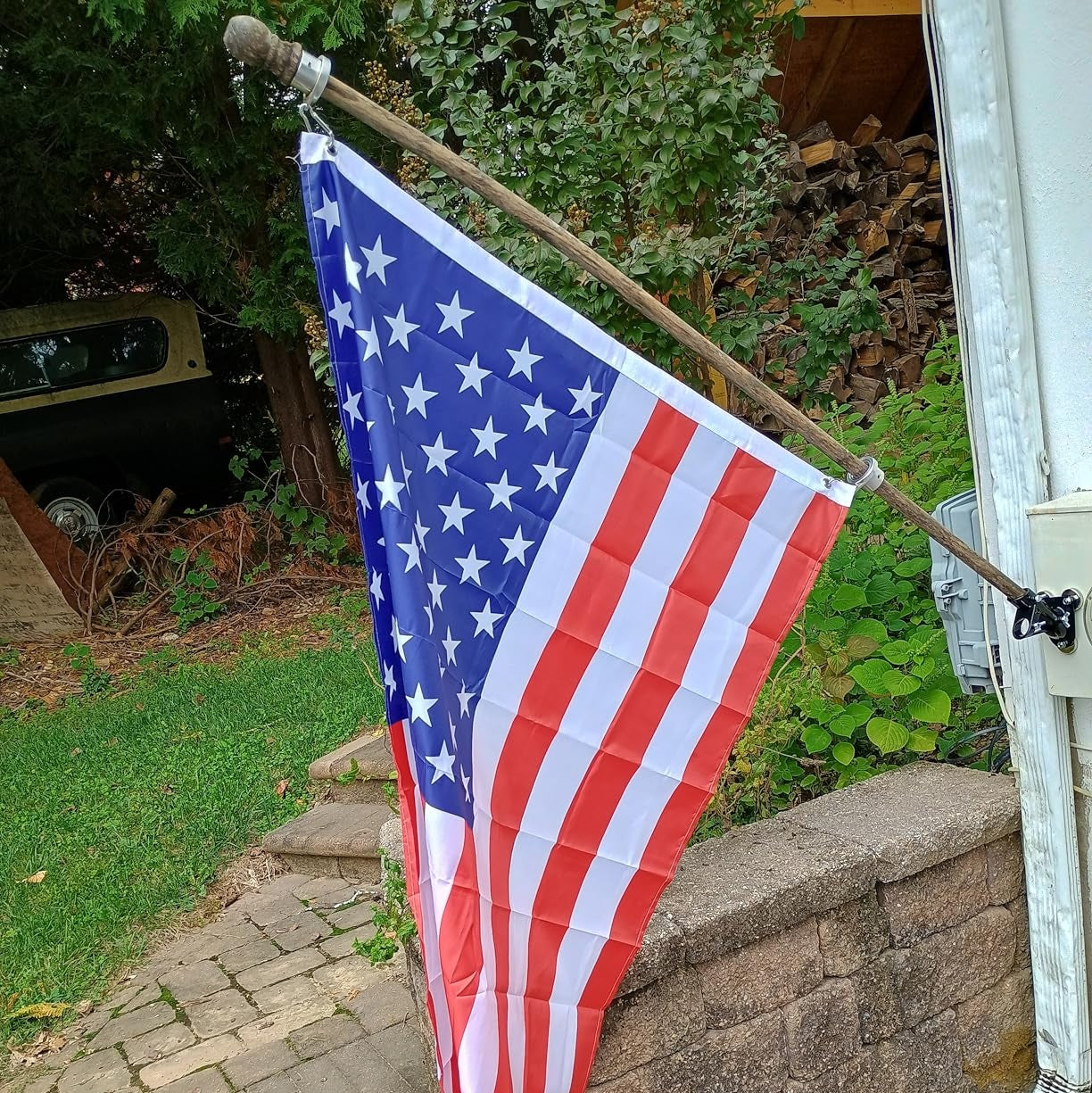 American flag displayed on house using wall mount bracket showing angled pole position for outdoor flag display
