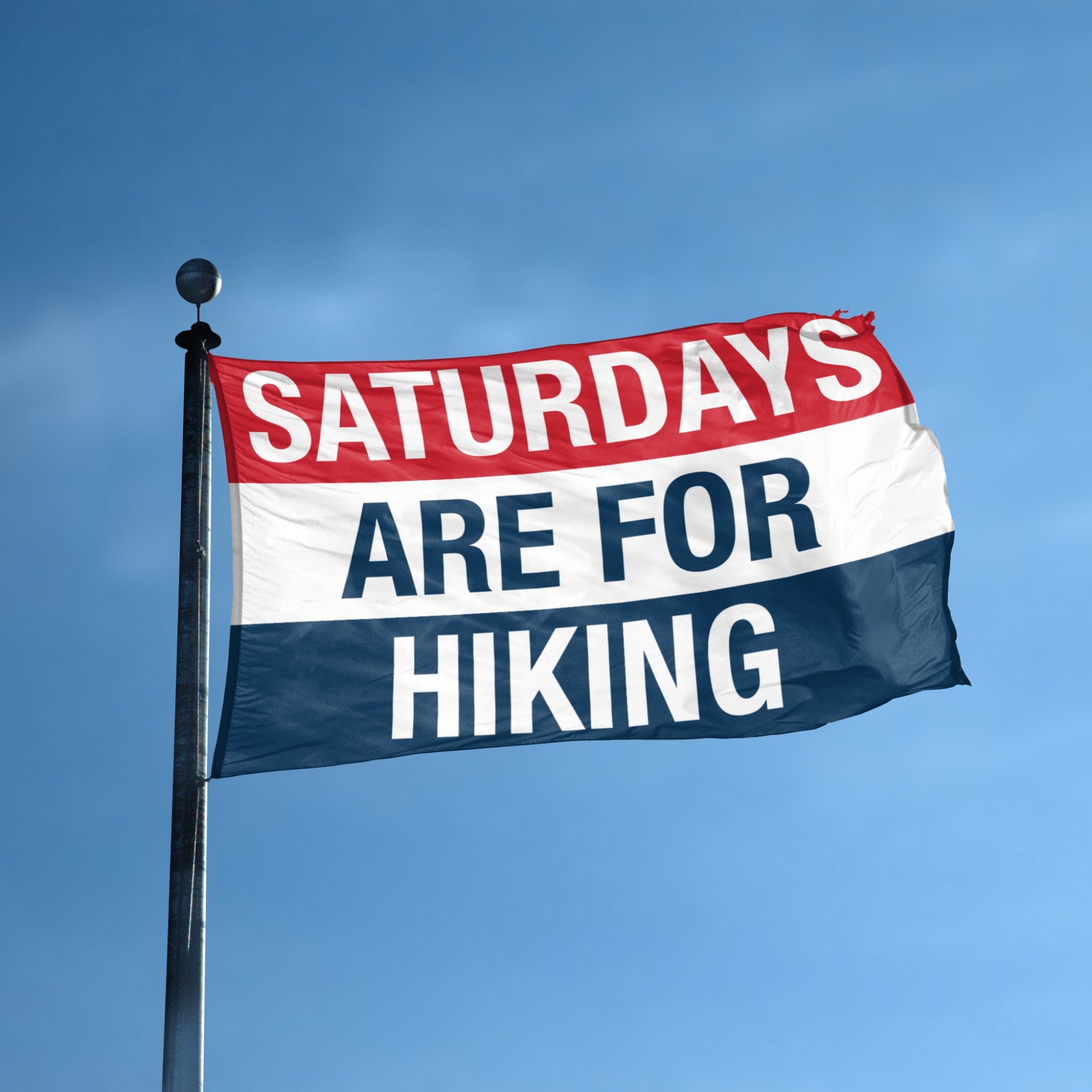 Flag with 'Saturdays are for Hiking' text against a blue sky