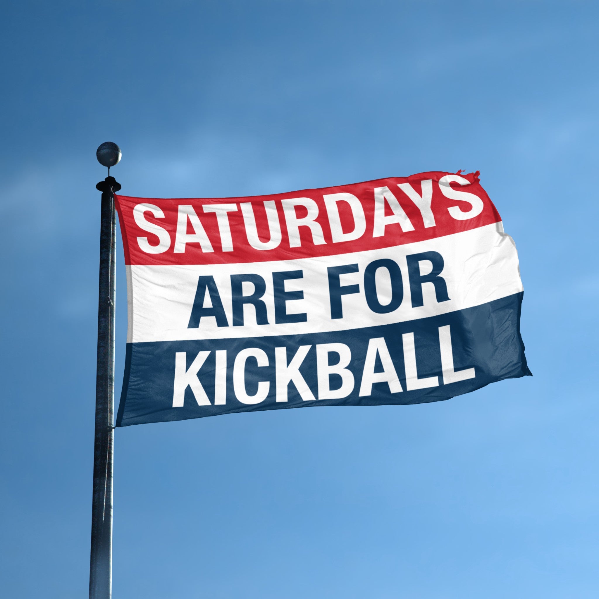 Flag with 'Saturdays are for Kickball' text against a blue sky
