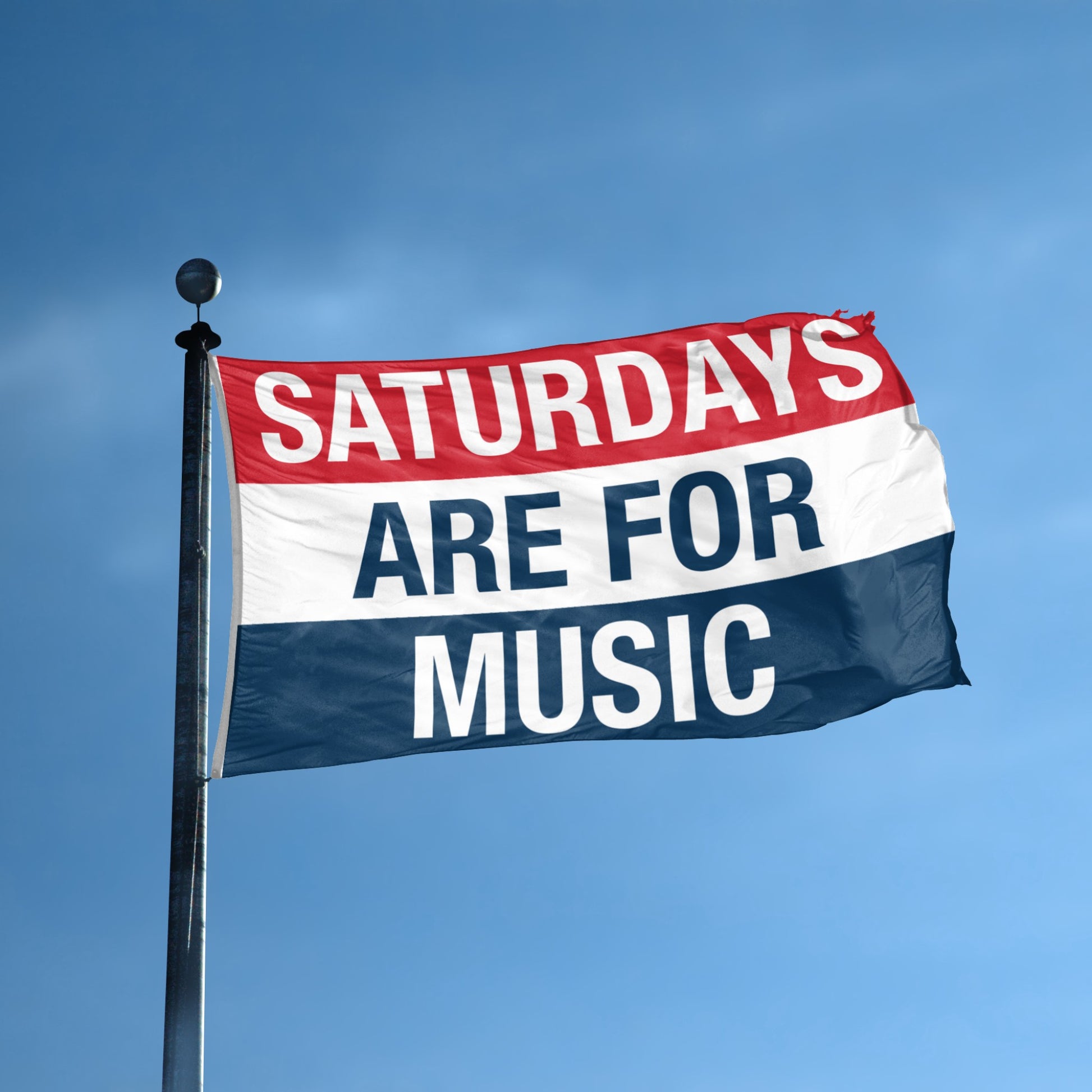 Flag with 'Saturdays are for music' text against a blue sky
