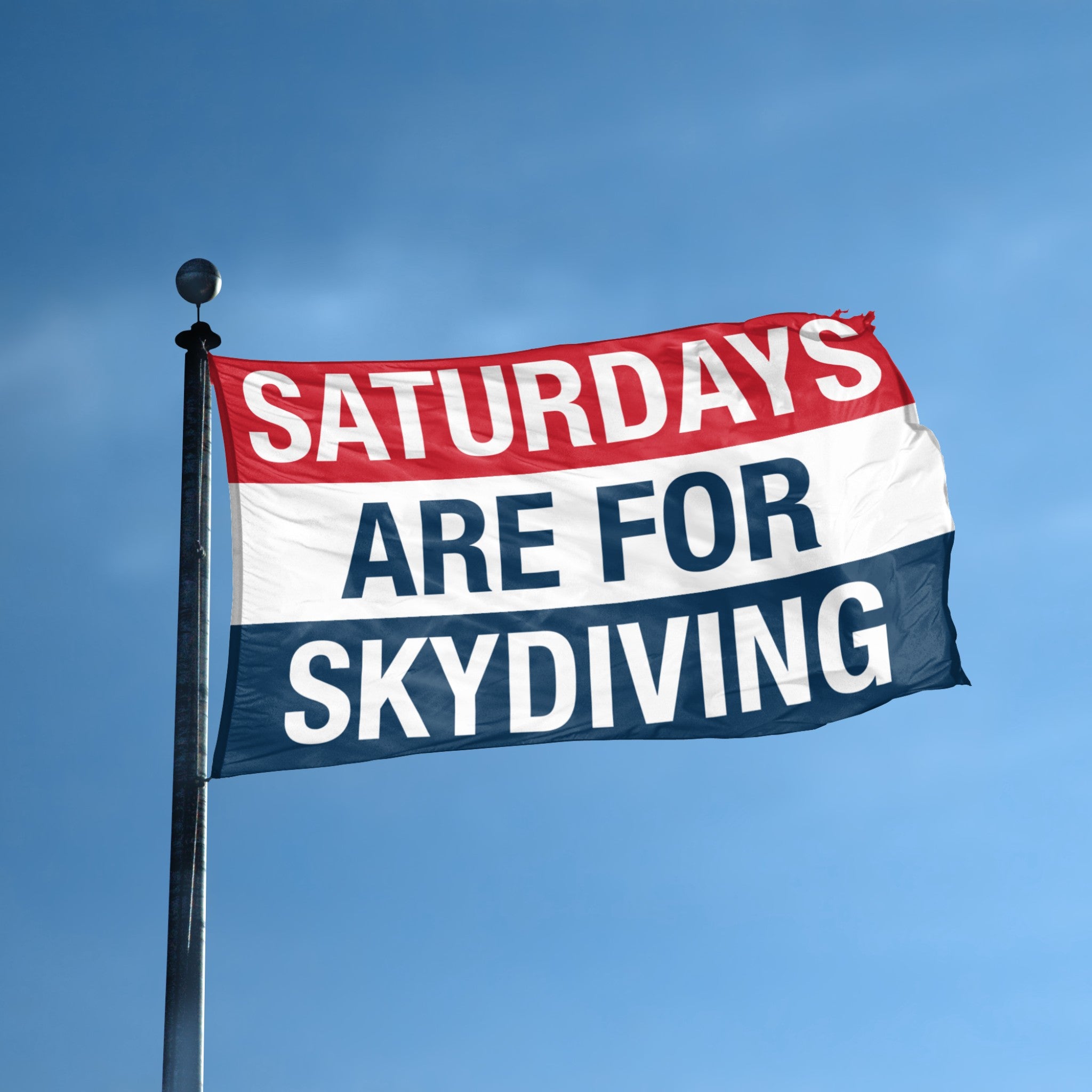 Flag with 'Saturdays are for Skydiving' text against a blue sky