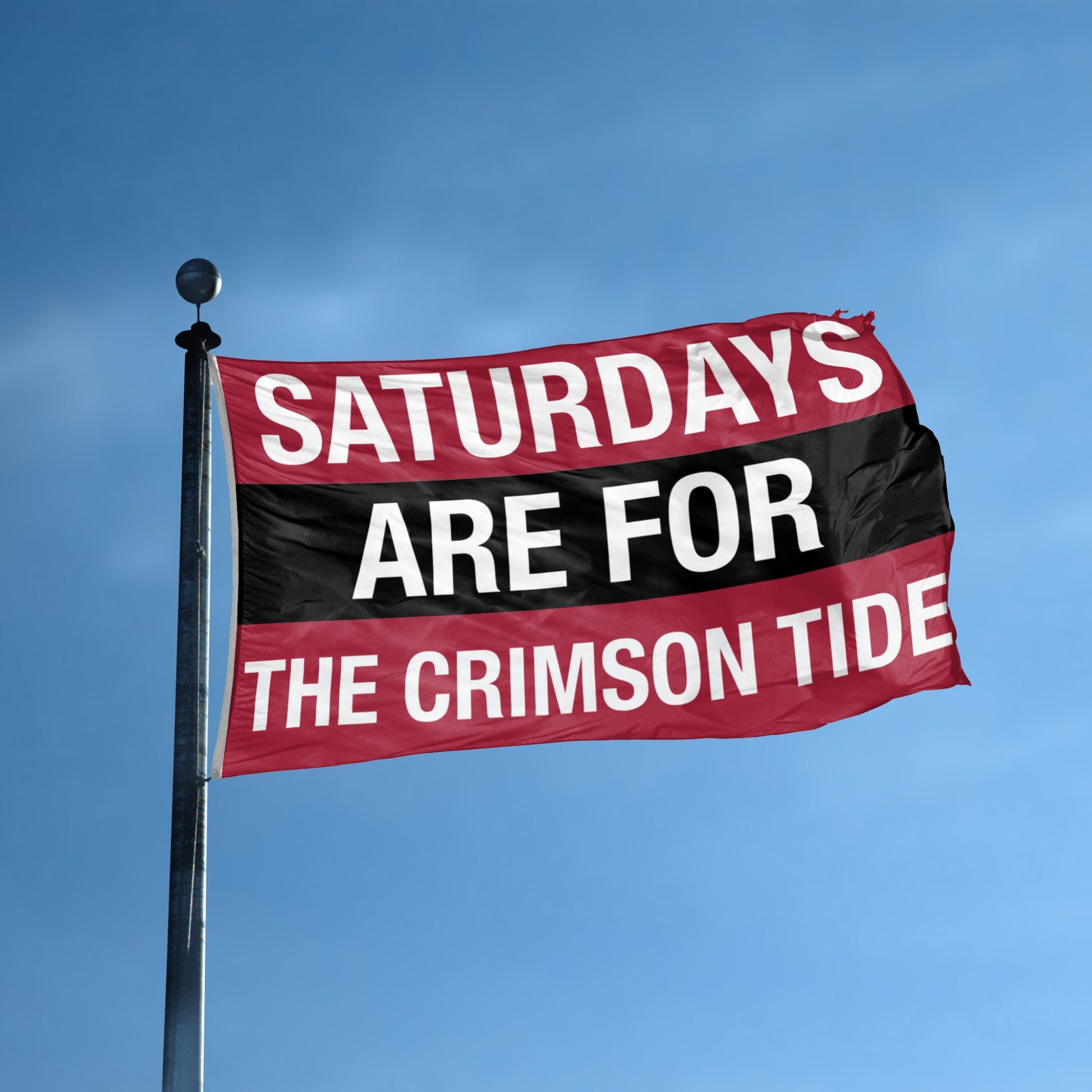 Flag with 'Saturdays are for the Crimson Tide' text against a blue sky