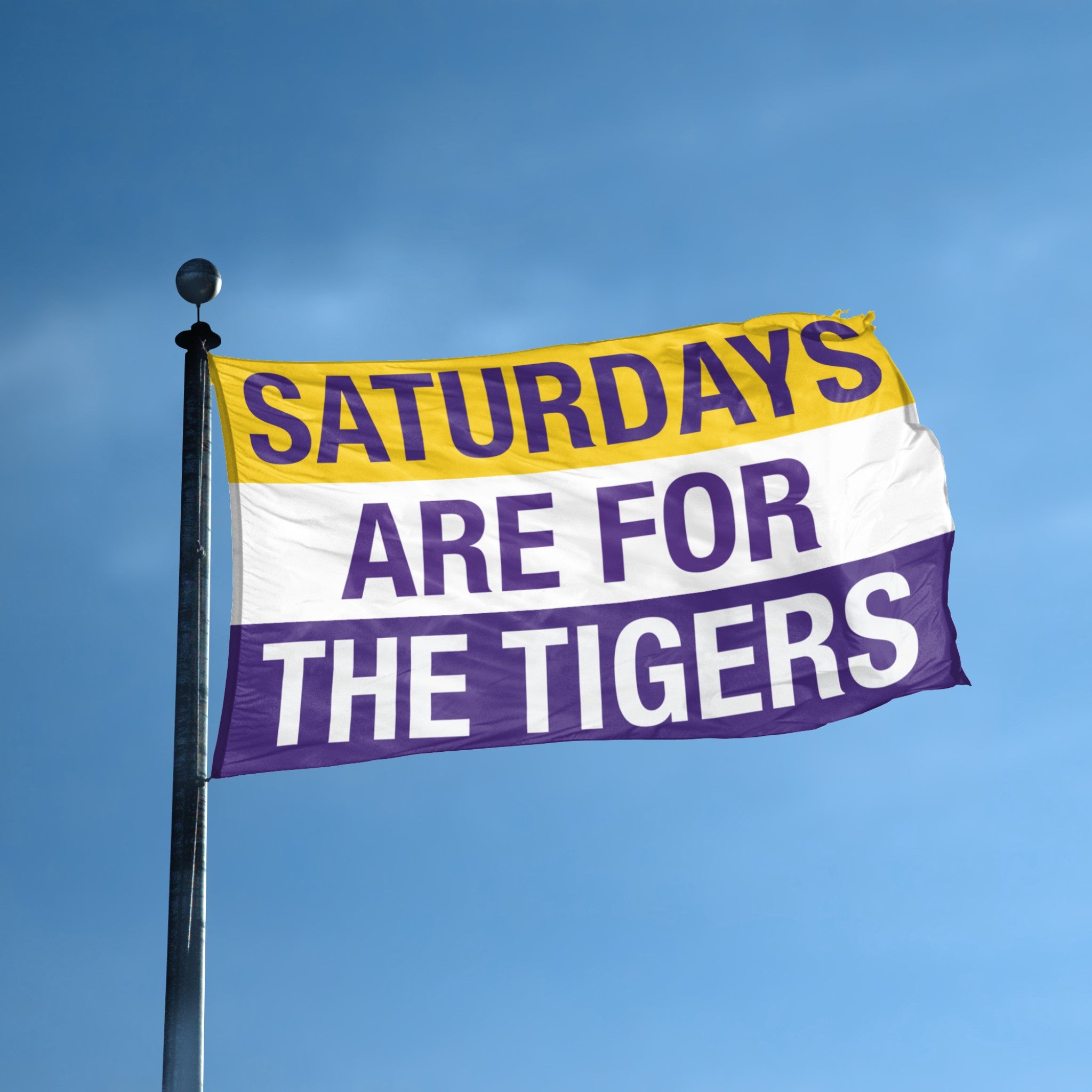 A flag flying on a flagpole with "saturdays are for the tigers" on a purple, gold and white background. 
