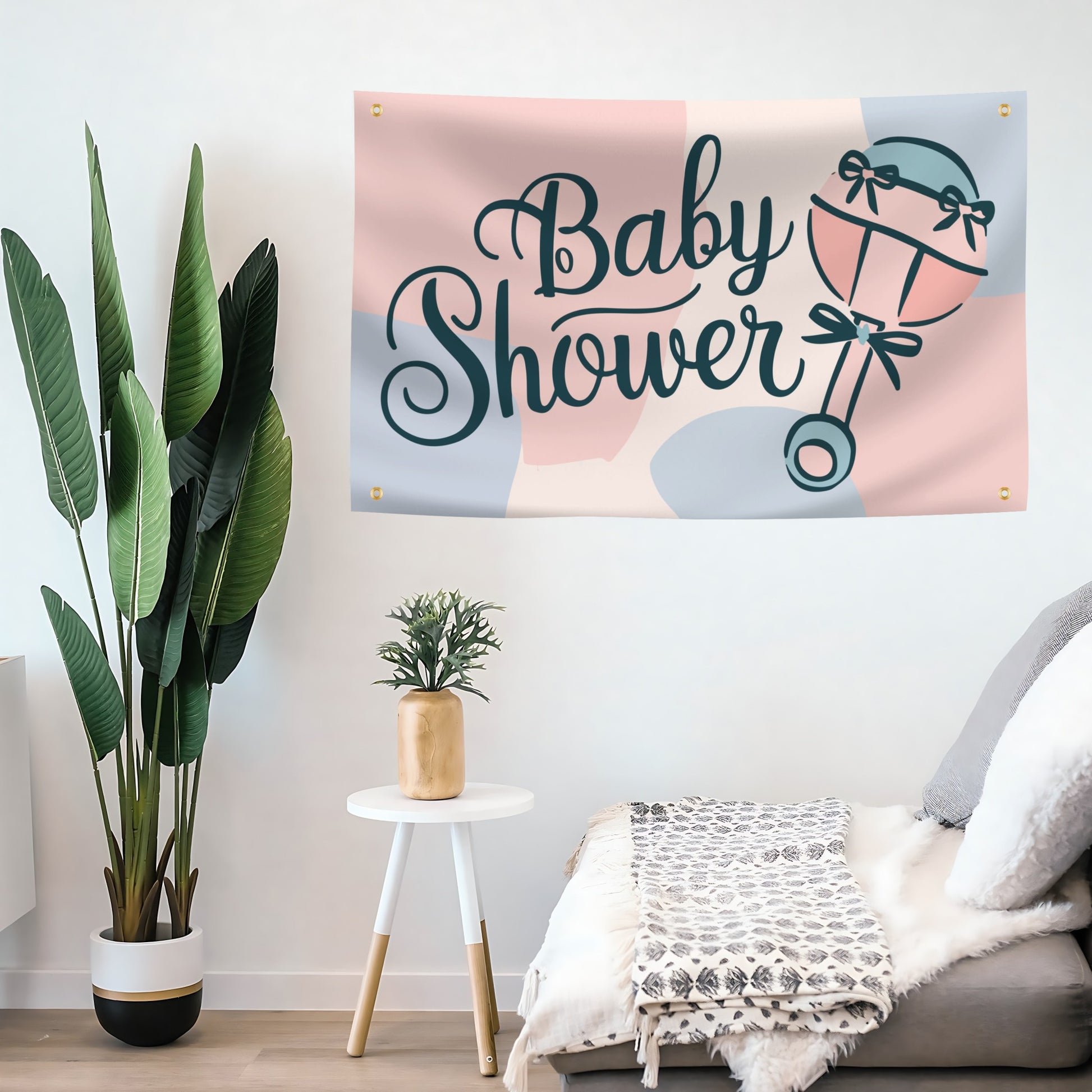 Baby shower flag banner with decorative elements on a wall above a sofa.