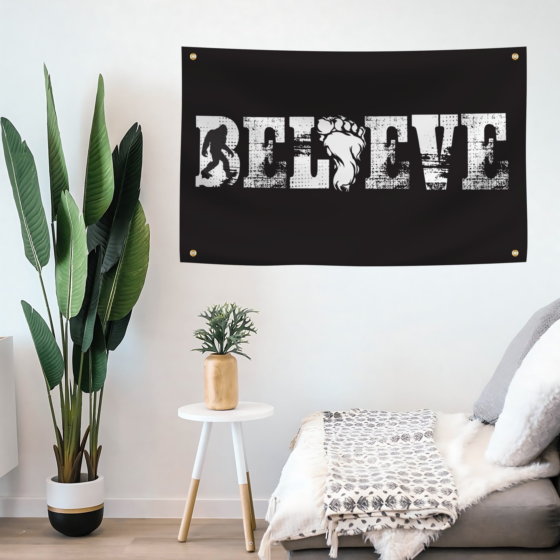 Black flag banner with 'BELIEVE' text and silhouette of bigfoot on a wall in a room 