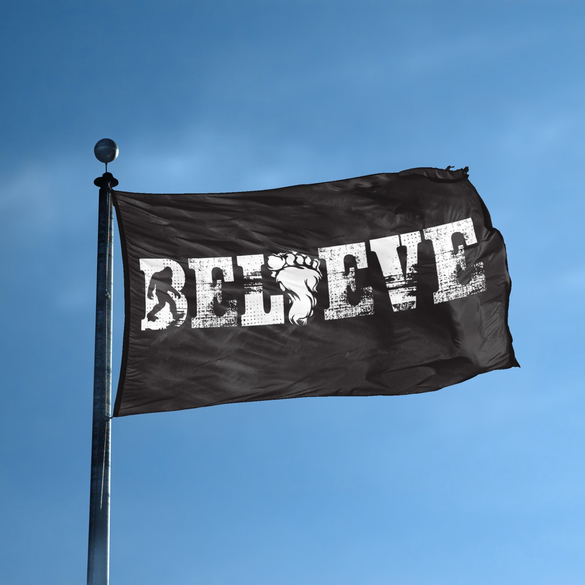 A flag with the theme "Bigfoot Believe" displayed on a tall flag pole and blue skies.