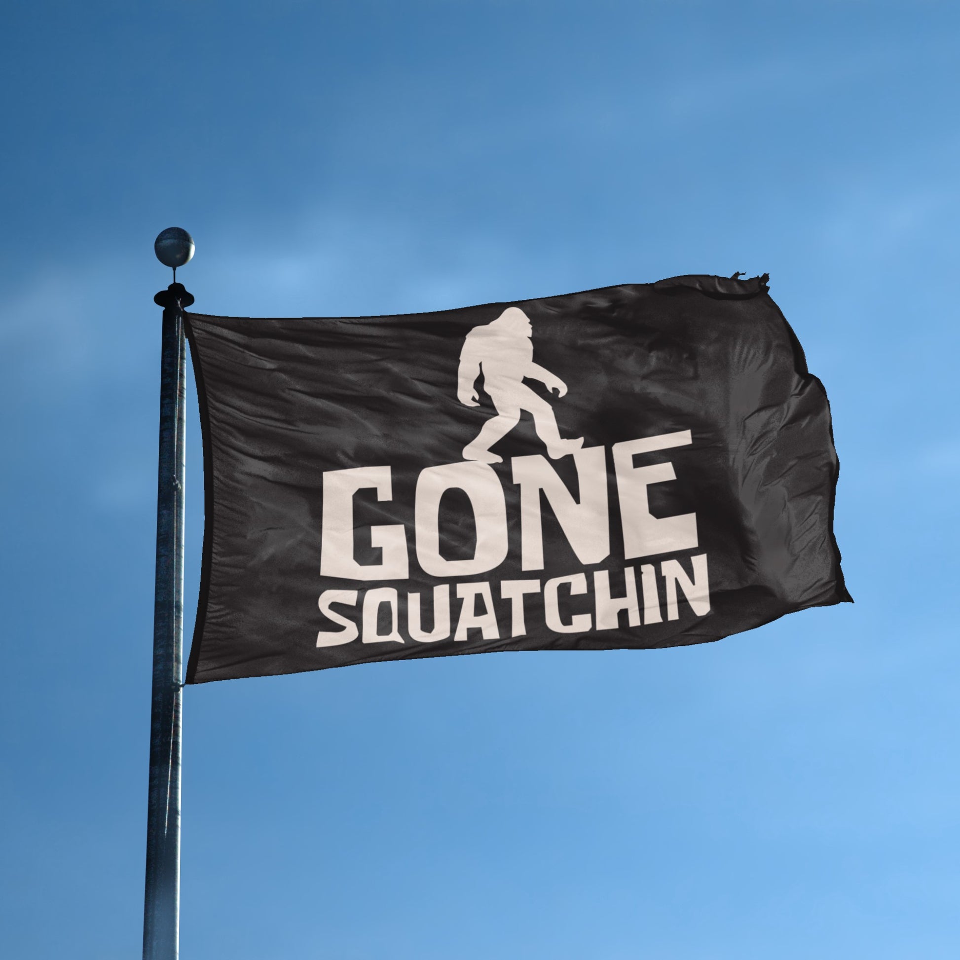 A flag with the theme "Bigfoot Gone Squatchin" displayed on a tall flag pole and blue skies.