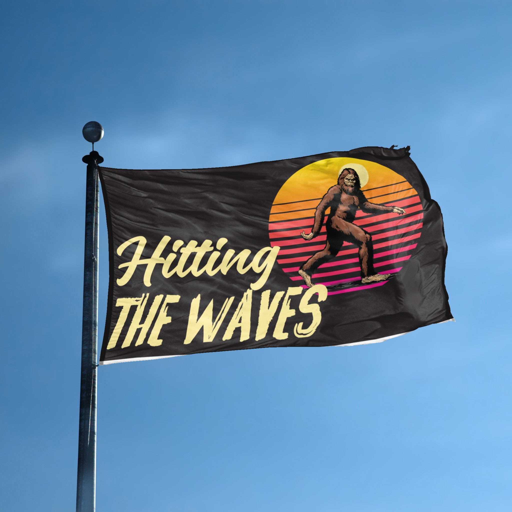 A flag with the theme "Bigfoot Hitting The Waves" displayed on a tall flag pole and blue skies.