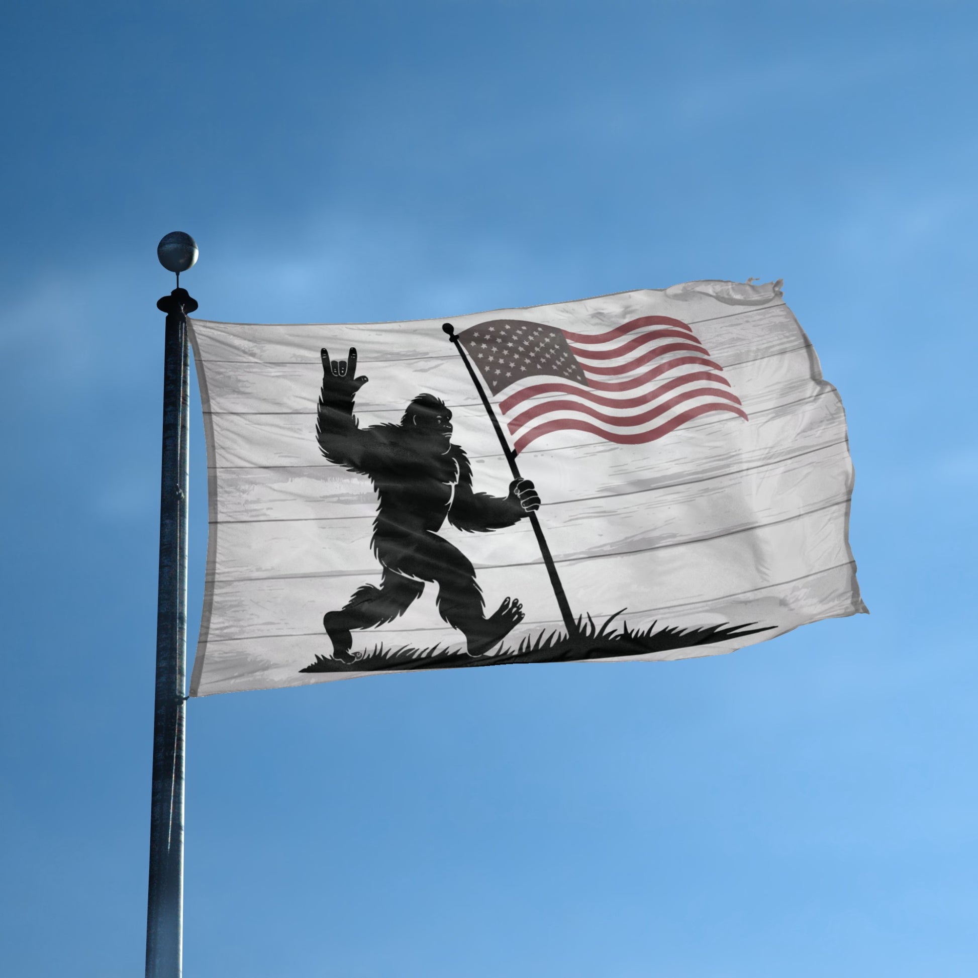 A flag with the theme "Bigfoot Rock On Patriotic" displayed on a tall flag pole and blue skies.