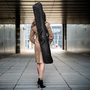 Person walking with a long black feather flag carrying bag on a city street