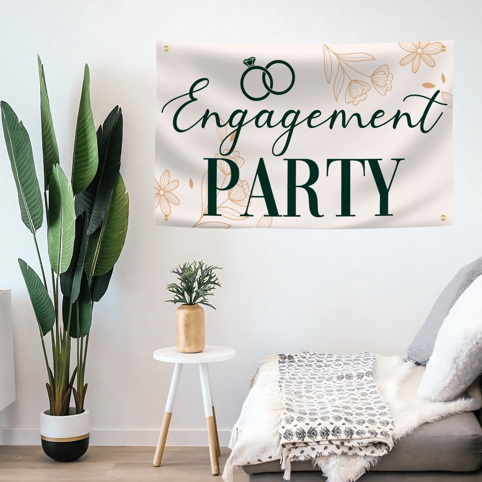 Engagement party banner hanging on a wall with plants and a small table in the foreground.