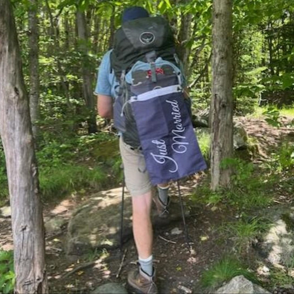 Person hiking in a forest with a 'Just Married' backpack
