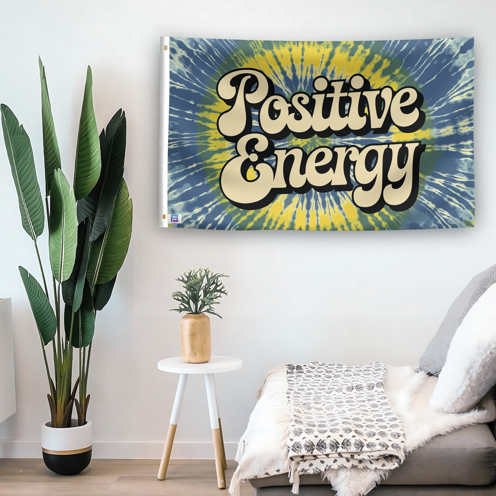 In a home setting, a flag with the saying "Positive Energy" is mounted on a white wall by a side table.