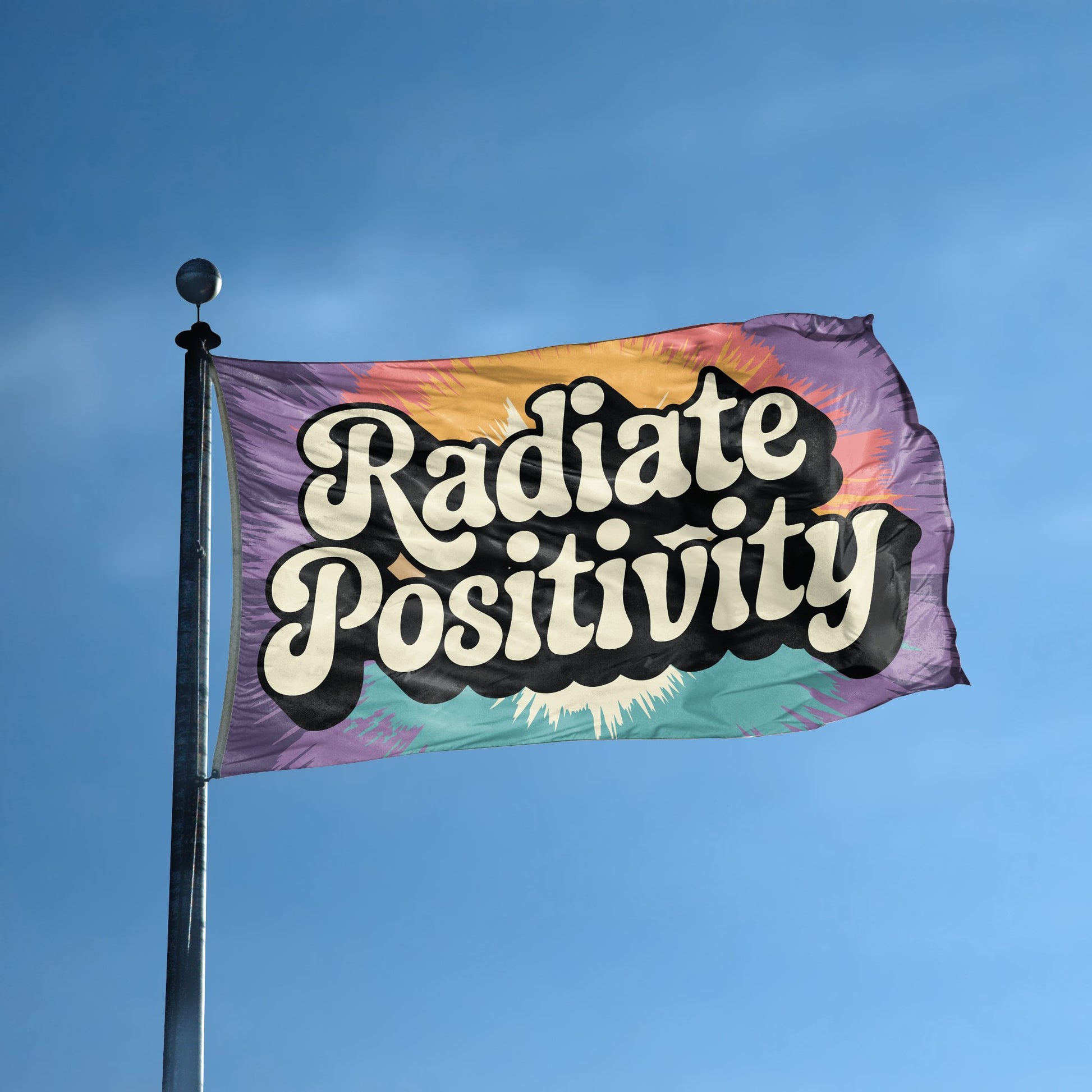 A flag with the saying "Radiate Positivity" displayed on a high pole, with a tie dye style color scheme.