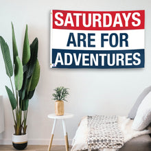 Load image into Gallery viewer, In a home setting, a flag with the saying &quot;https://www.dropbox.com/scl/fi/a3uvnzeoqqspy2xpx88l1/saturdays-are-for-adventures_room.png?rlkey=dztbwnazw8t8gsw8o72quqydb&amp;raw=1&quot; is mounted on a white wall by a side table.
