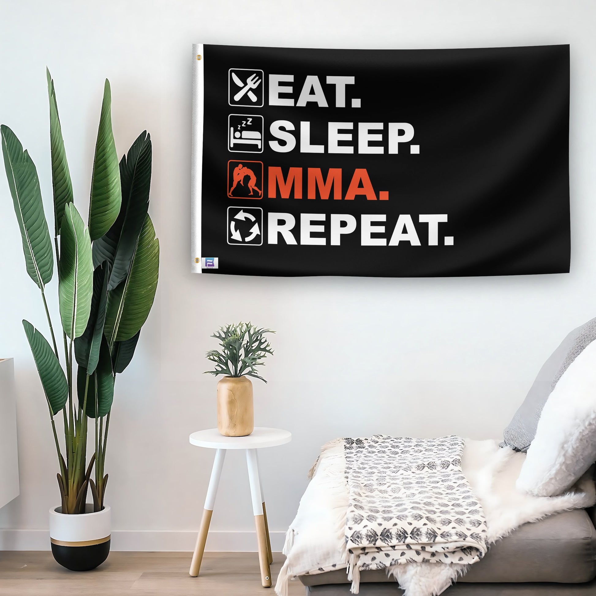 In a home setting, a flag with the saying "Eat Sleep MMA Repeat" is mounted on a white wall by a side table.