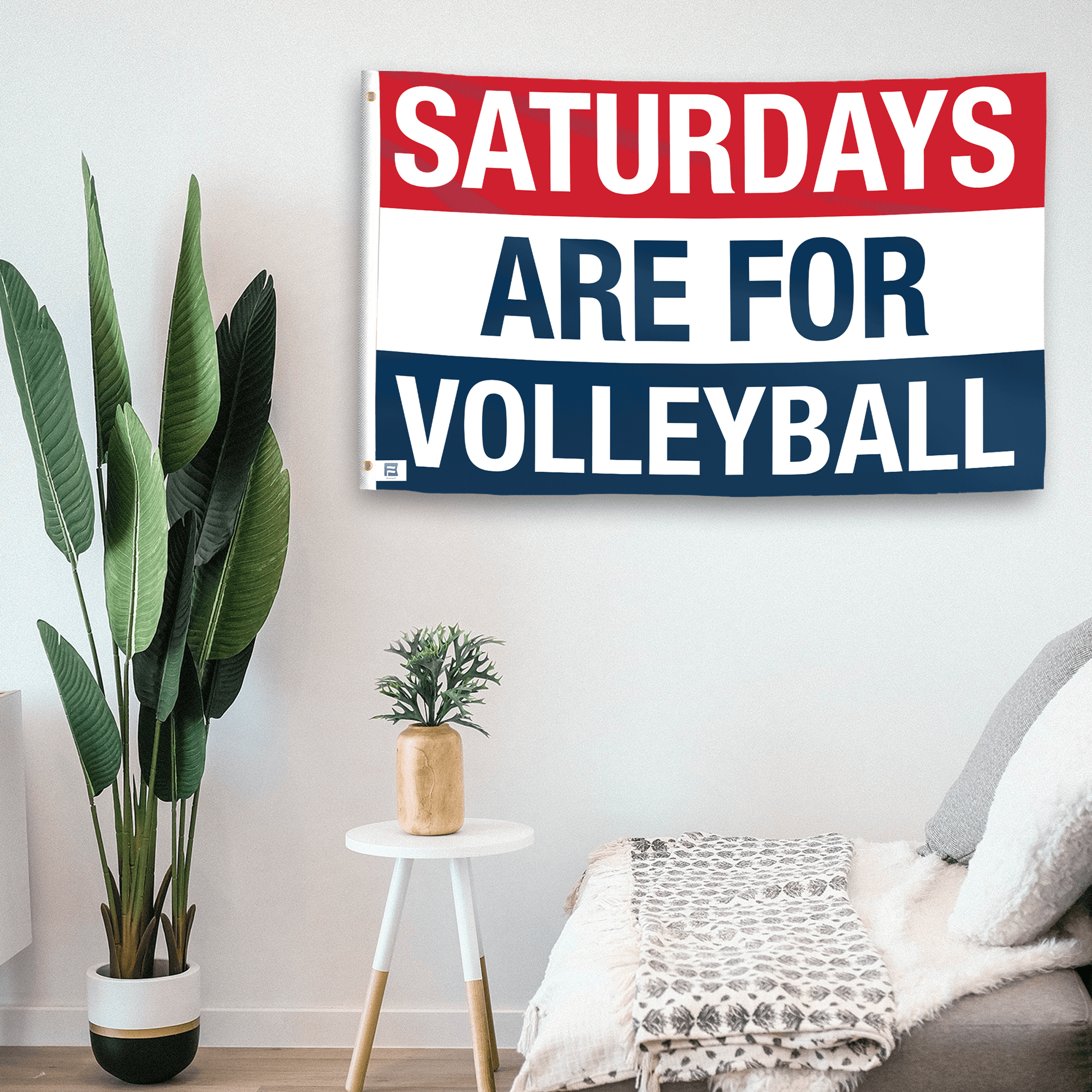 In a home setting, a flag with the saying "https://www.dropbox.com/scl/fi/dr2rgojw8ykjznfvap3j3/saturdays-are-for-volleyball_room.png?rlkey=aunqdbfjmylwy11zsblj7e834&raw=1" is mounted on a white wall by a side table.