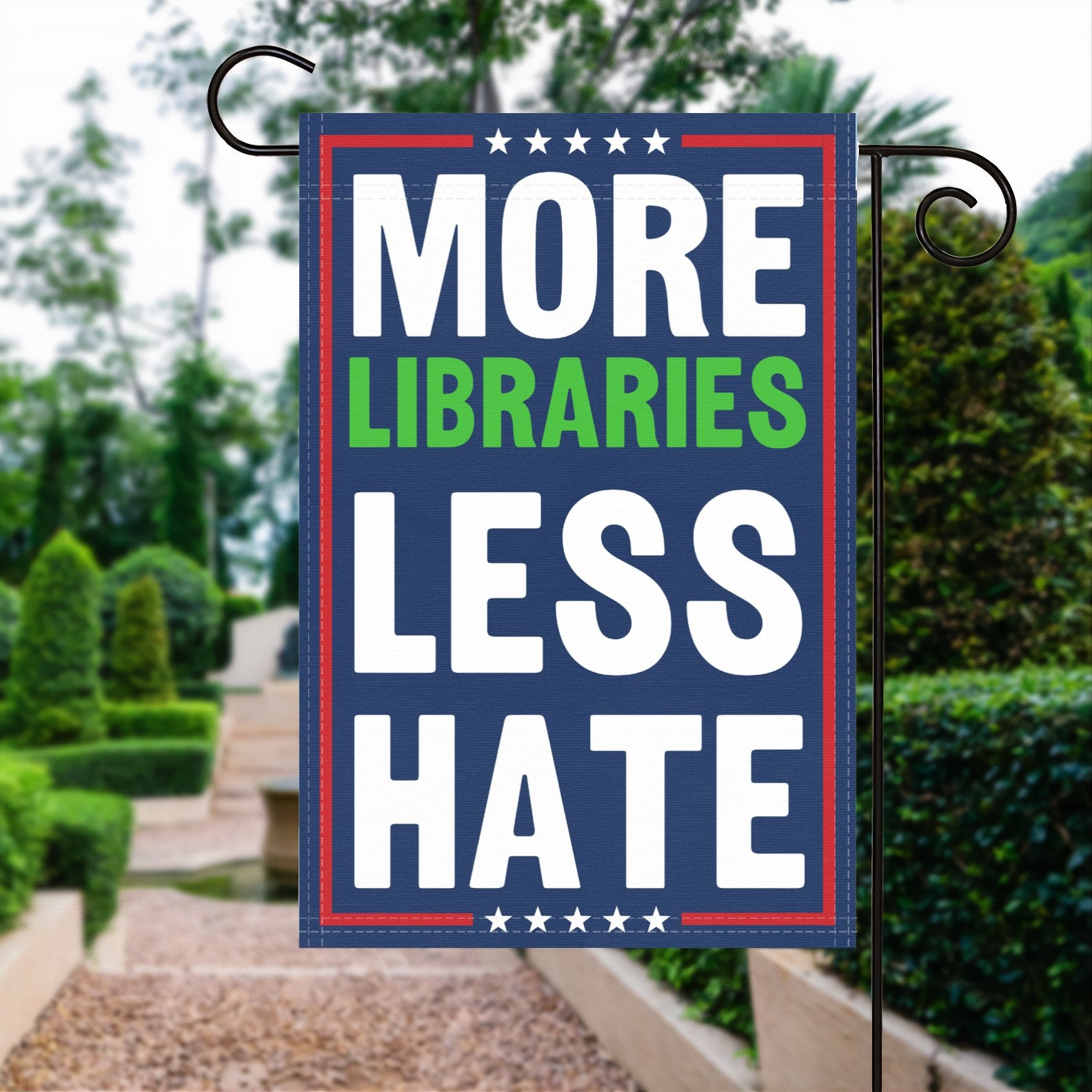 A red, white and blue political garden flag with the slogan More Libraries Less Hate.