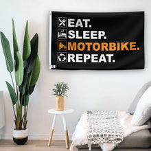 Load image into Gallery viewer, In a home setting, a flag with the saying &quot;Eat Sleep Motorbike Repeat&quot; is mounted on a white wall by a side table.
