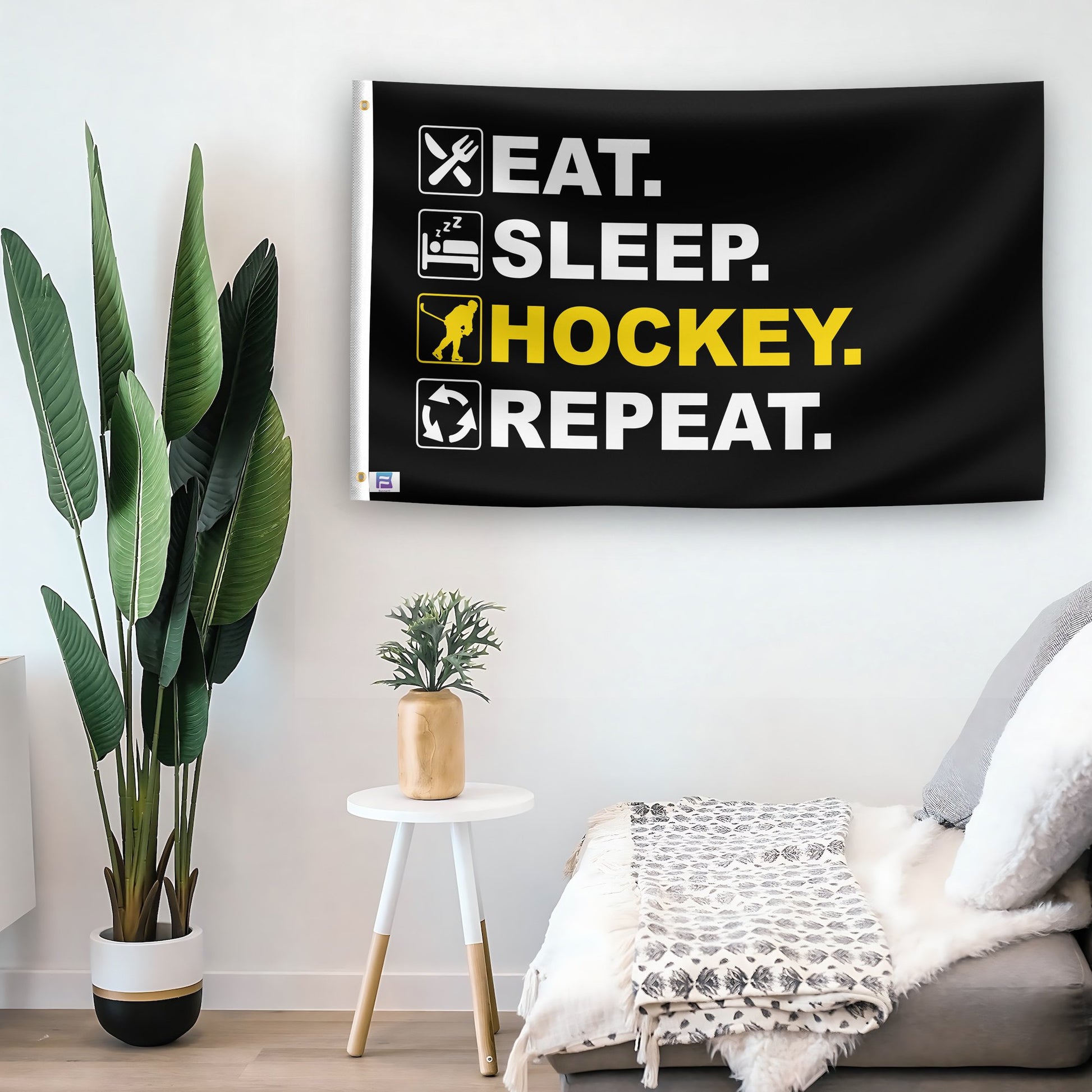 In a home setting, a flag with the saying "Eat Sleep Hockey Repeat" is mounted on a white wall by a side table.