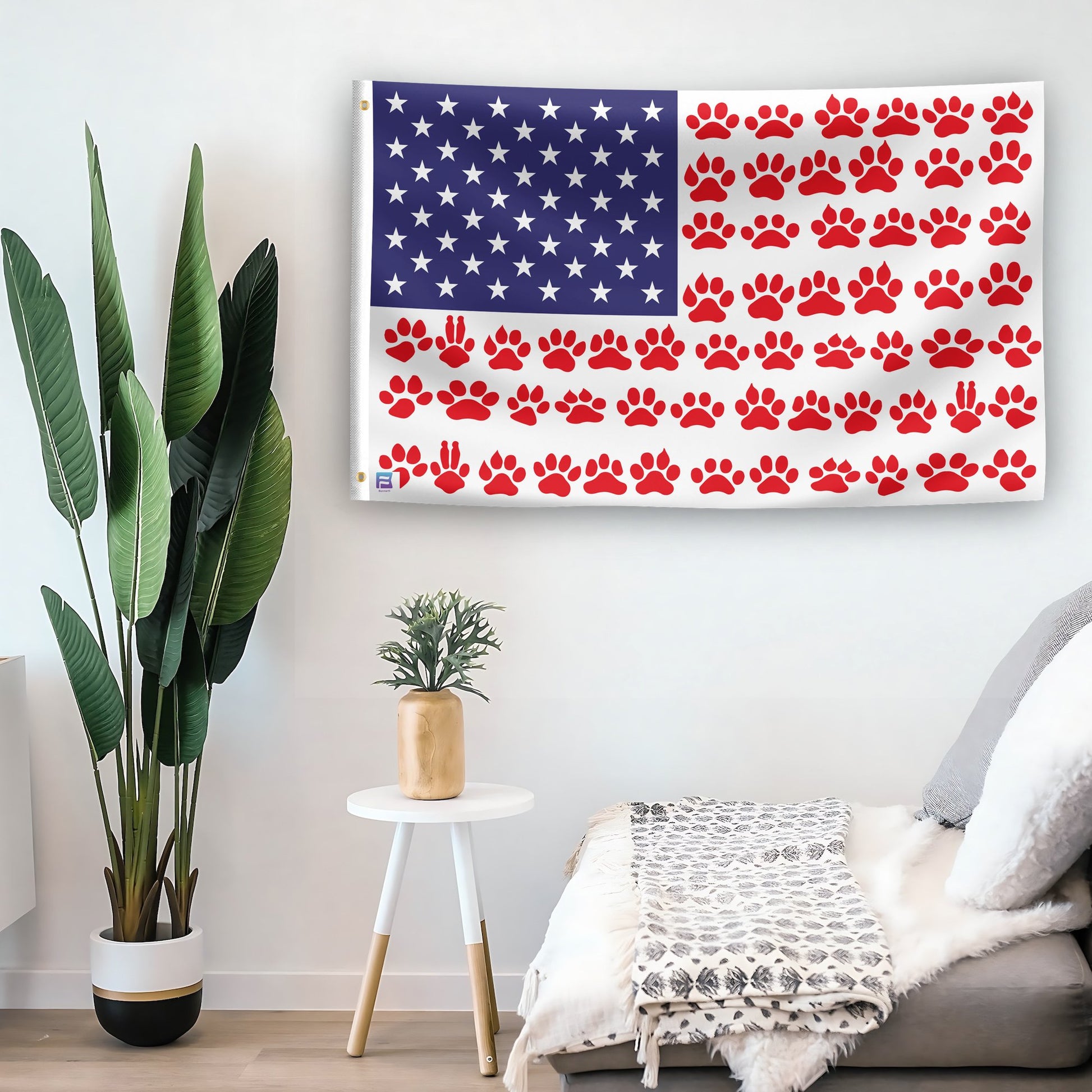 In a home setting, an american flag with the theme "Paw Prints Stripes American" is mounted on a white wall by a side table.