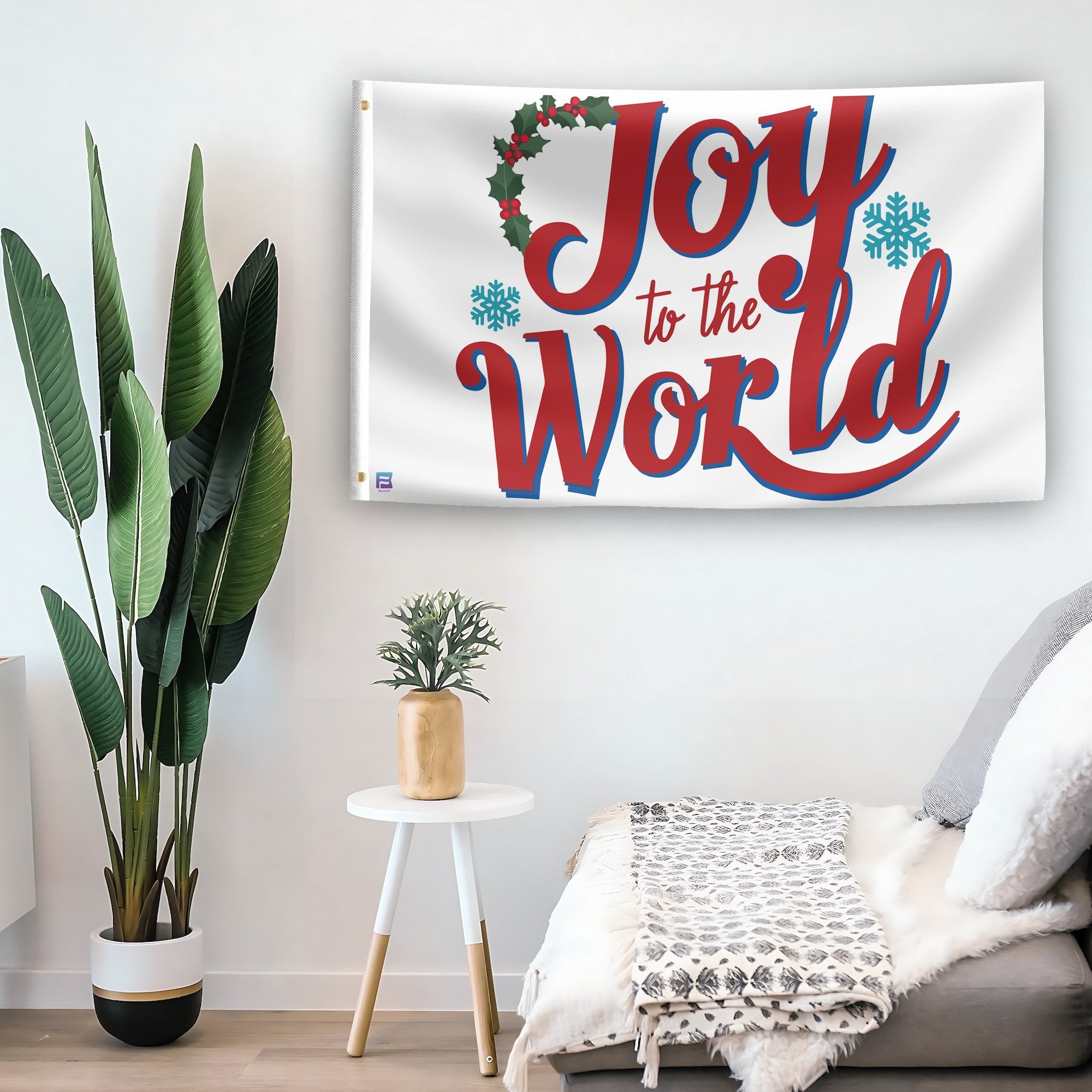 In a home setting, a flag with the saying "Joy To The World Christmas" is mounted on a white wall by a side table.