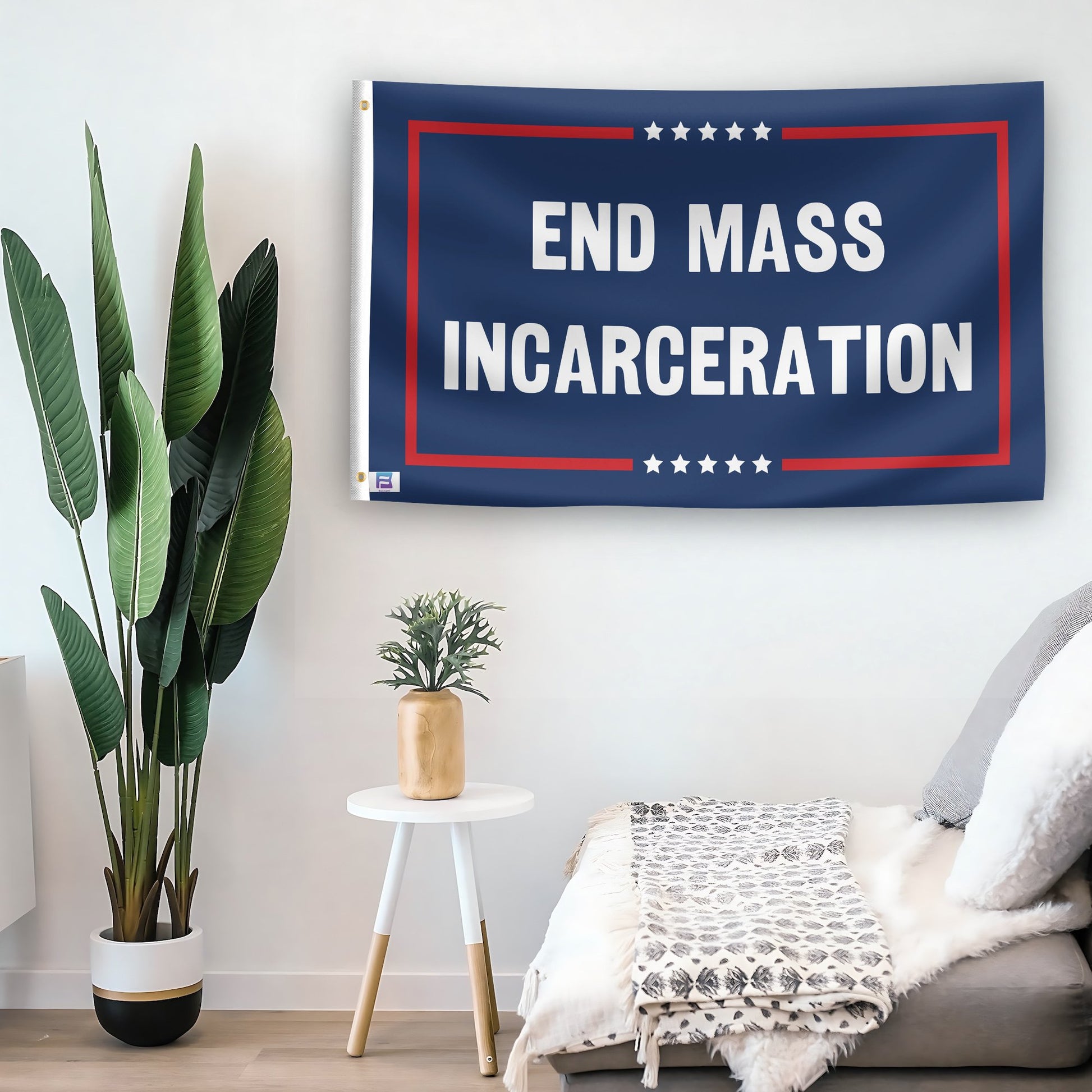 In a home setting, a flag with the saying "End Mass Incarceration Political" is mounted on a white wall by a side table.