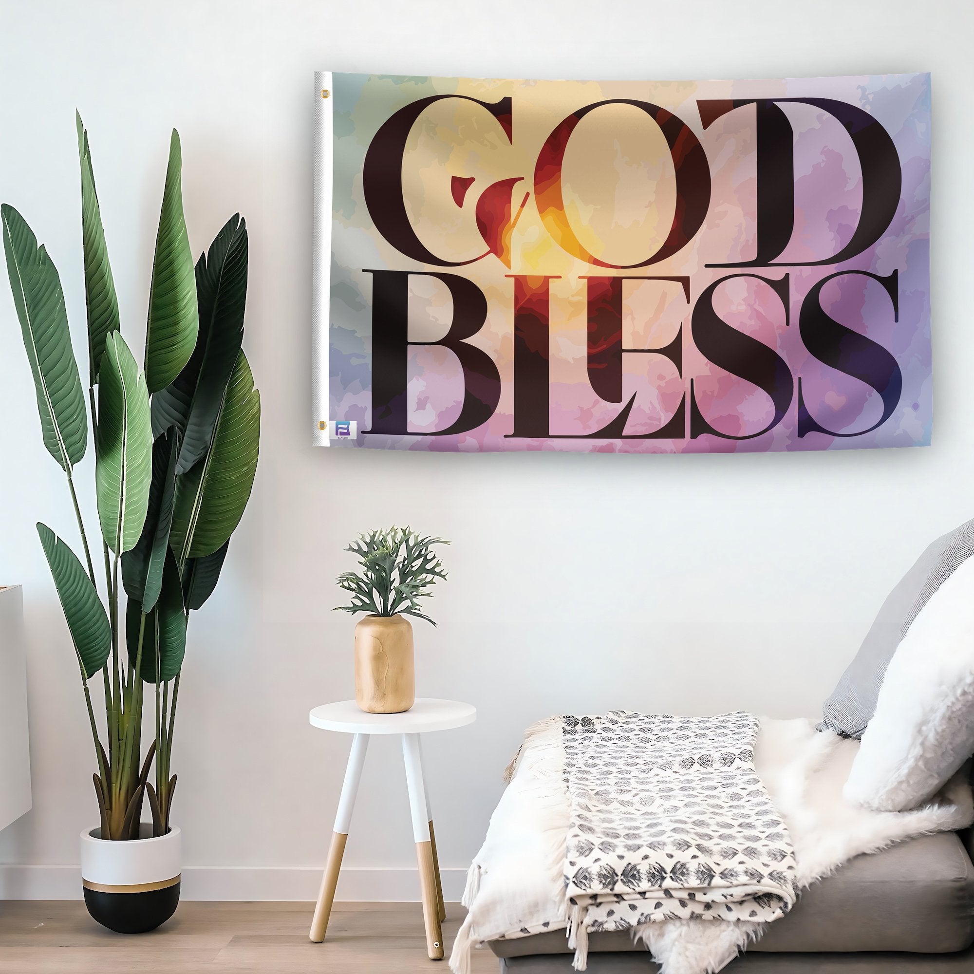 In a home setting, a flag with the saying "God Bless" is mounted on a white wall by a side table.