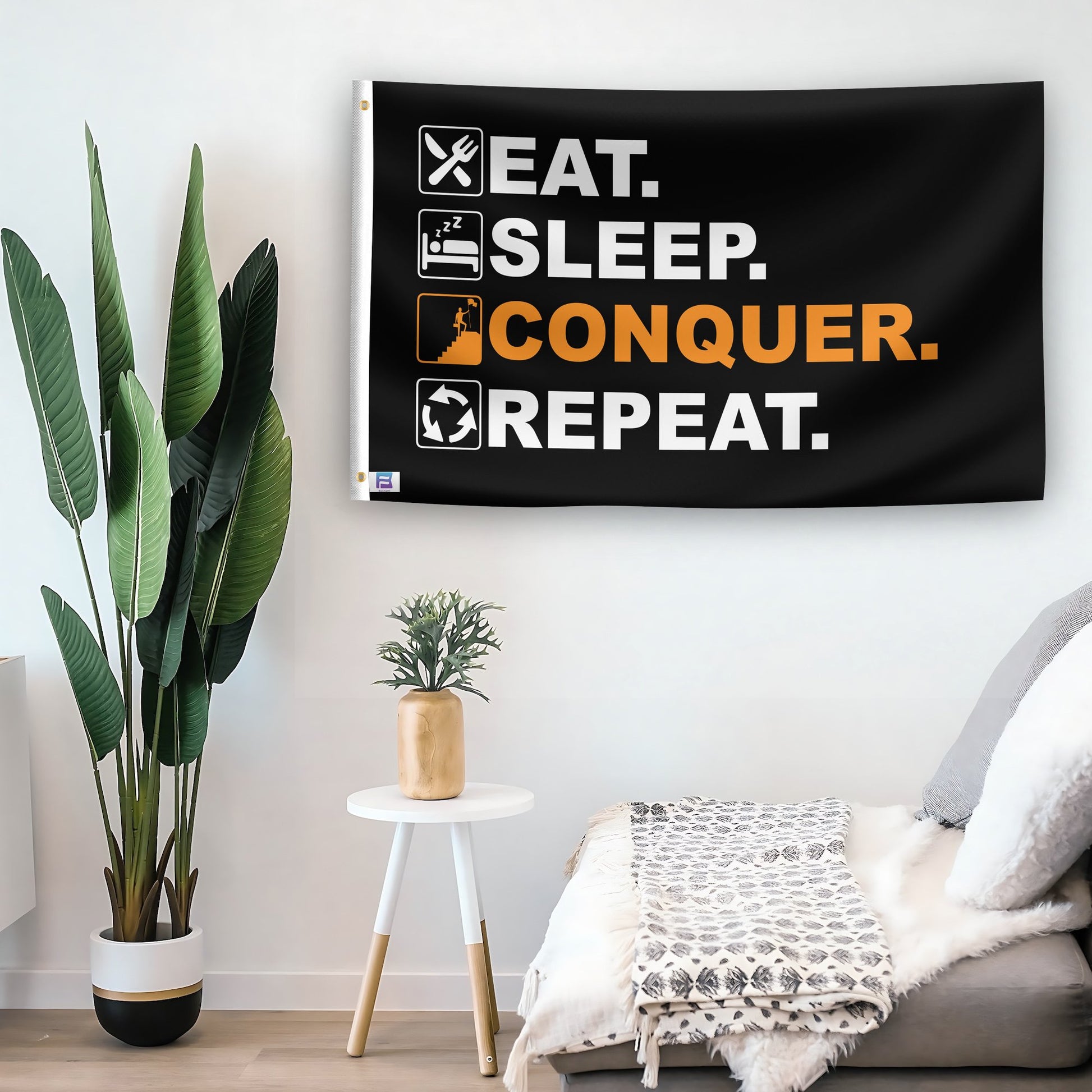 In a home setting, a flag with the saying "Eat Sleep Conquer Repeat" is mounted on a white wall by a side table.