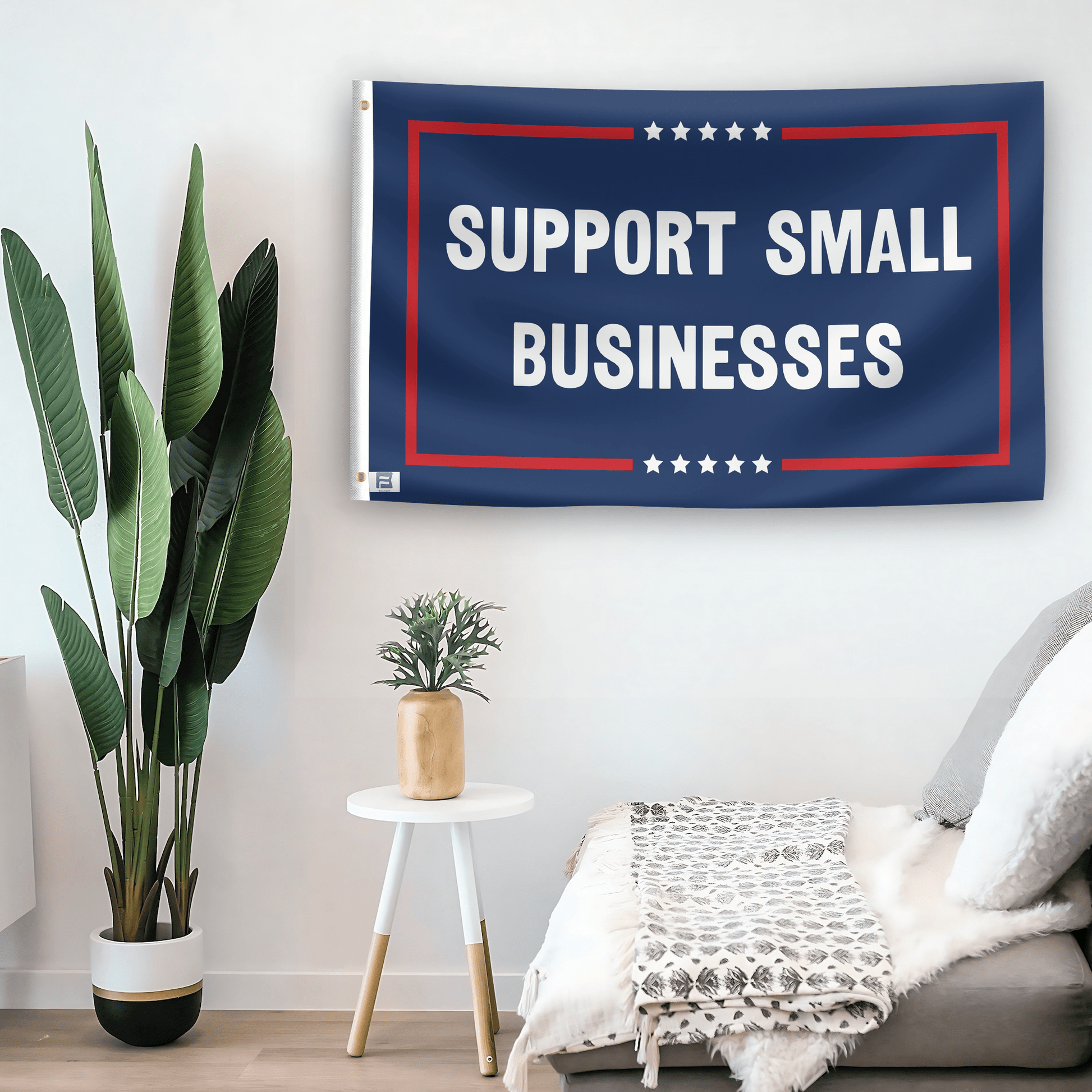 In a home setting, a flag with the saying "Support Small Businesses Political" is mounted on a white wall by a side table.