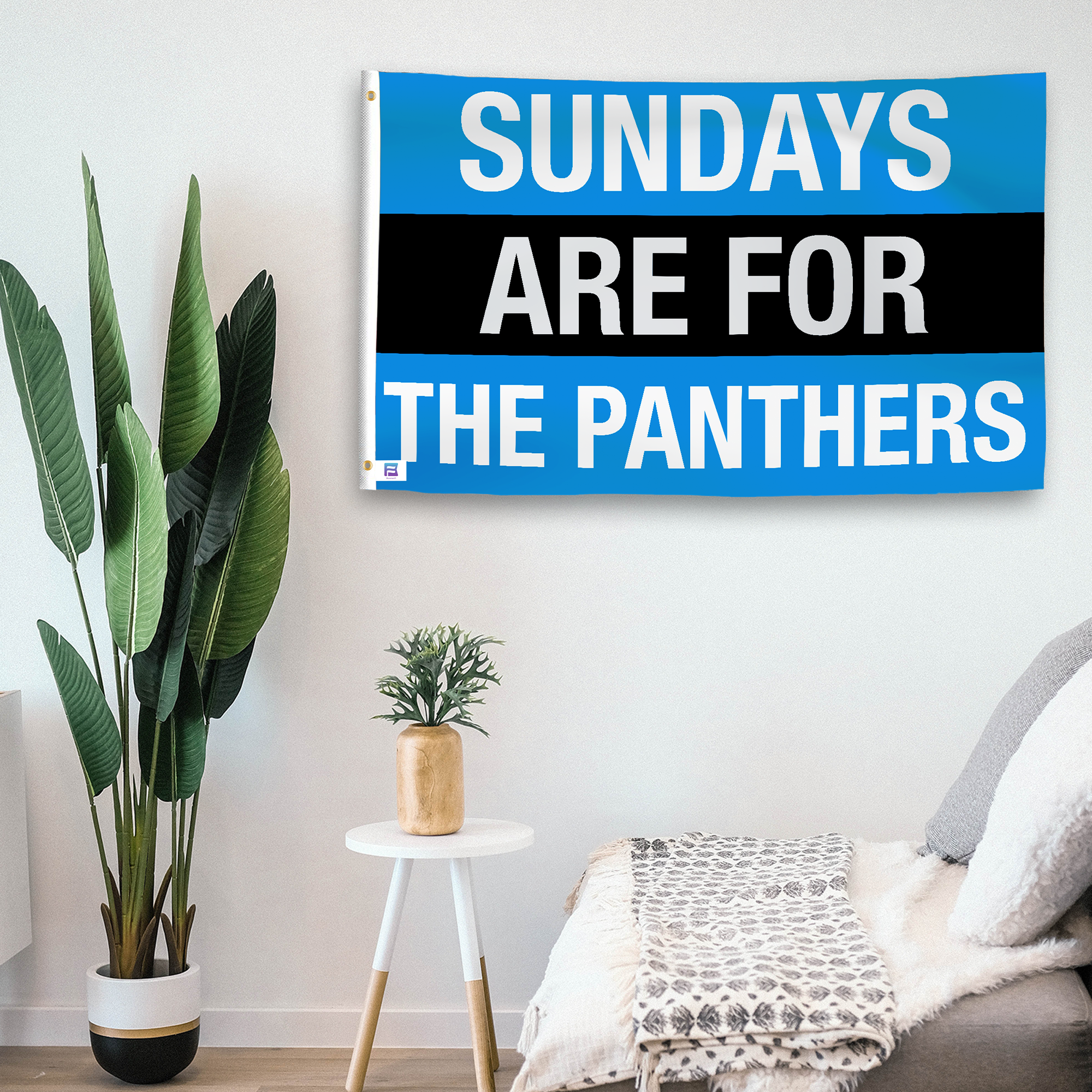 In a home setting, a flag with the saying "https://www.dropbox.com/scl/fi/t4x1es2ano1ne8lh4bw43/sundays-are-for-the-panthers_room.png?rlkey=4rnks5bax9v6a3nc6hs1gyy7f&raw=1" is mounted on a white wall by a side table.