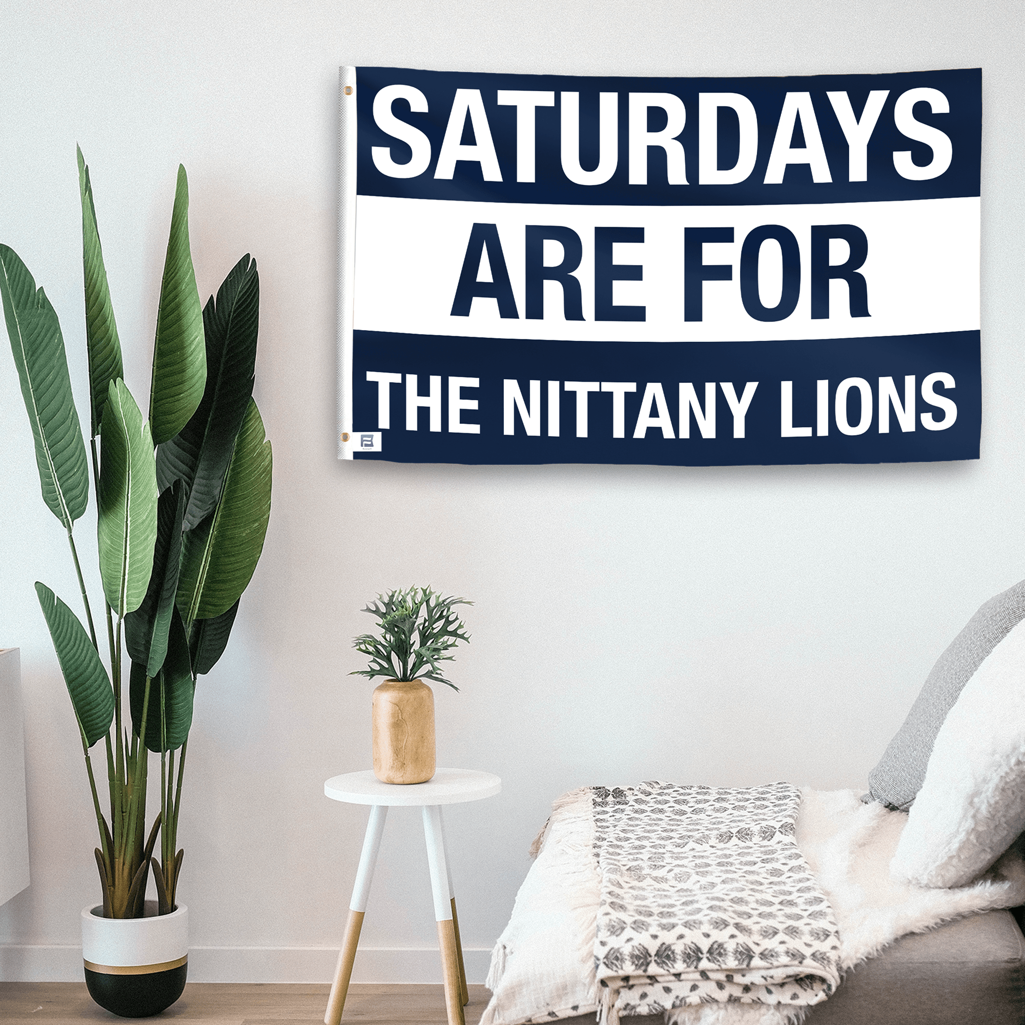 In a home setting, a flag with the saying "Saturdays Are for the Nittany Lions" is mounted on a white wall by a side table.