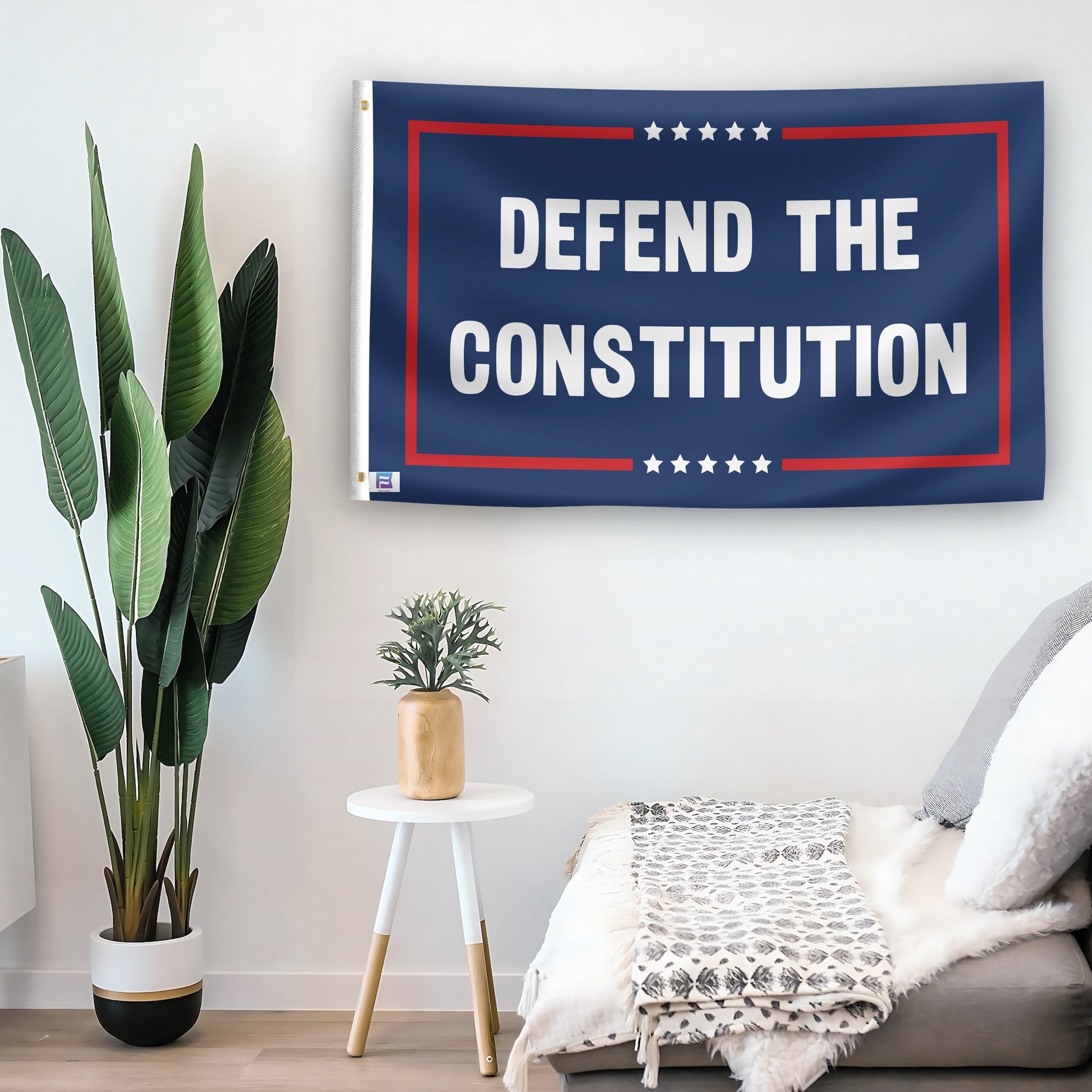 In a home setting, a flag with the saying "Defend The Constitution Political" is mounted on a white wall by a side table.