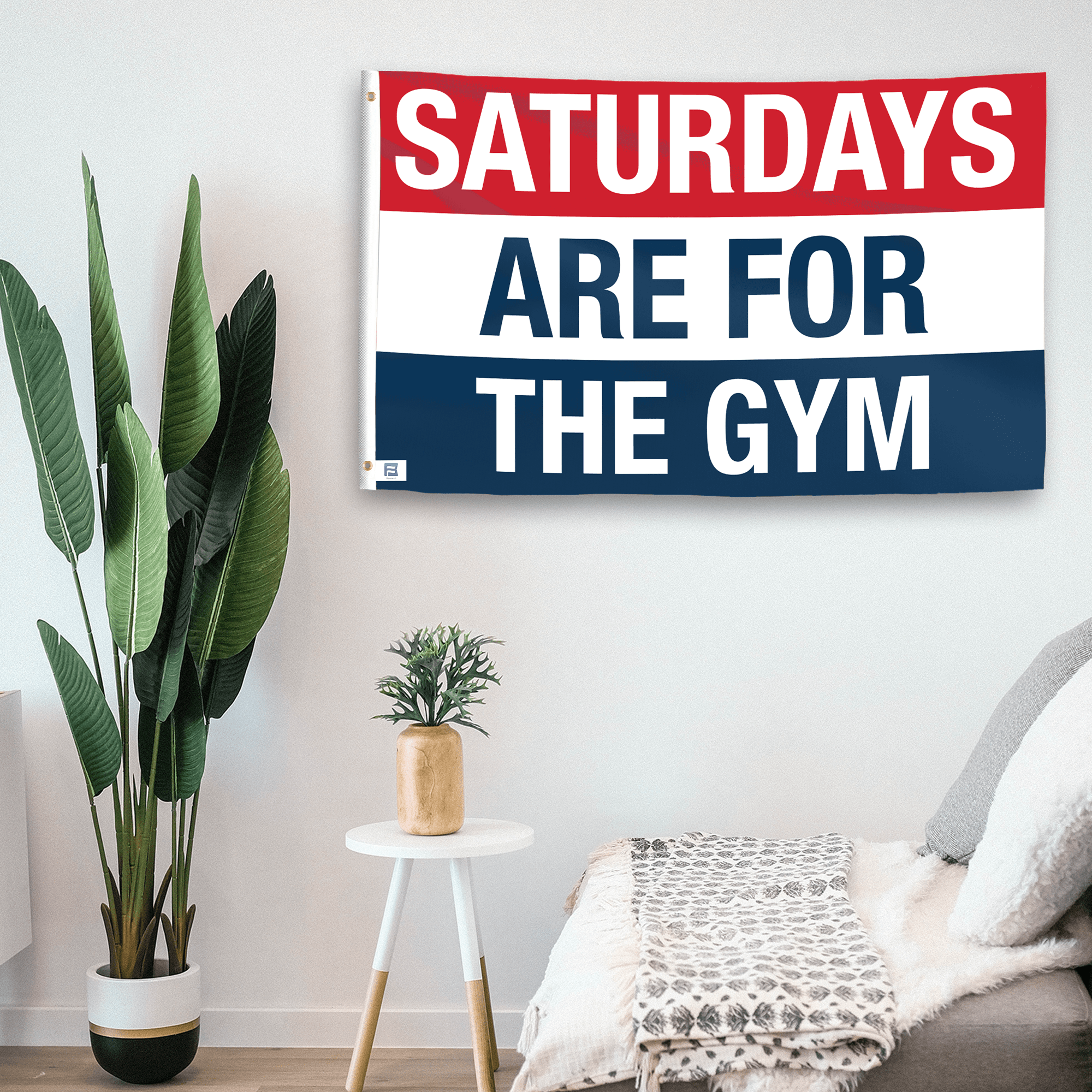 In a home setting, a flag with the saying "https://www.dropbox.com/scl/fi/zoads1shd0f2t04izyoyn/saturdays-are-for-the-gym_room.png?rlkey=ibh31p0dgdk9npbwty3npa2fu&raw=1" is mounted on a white wall by a side table.