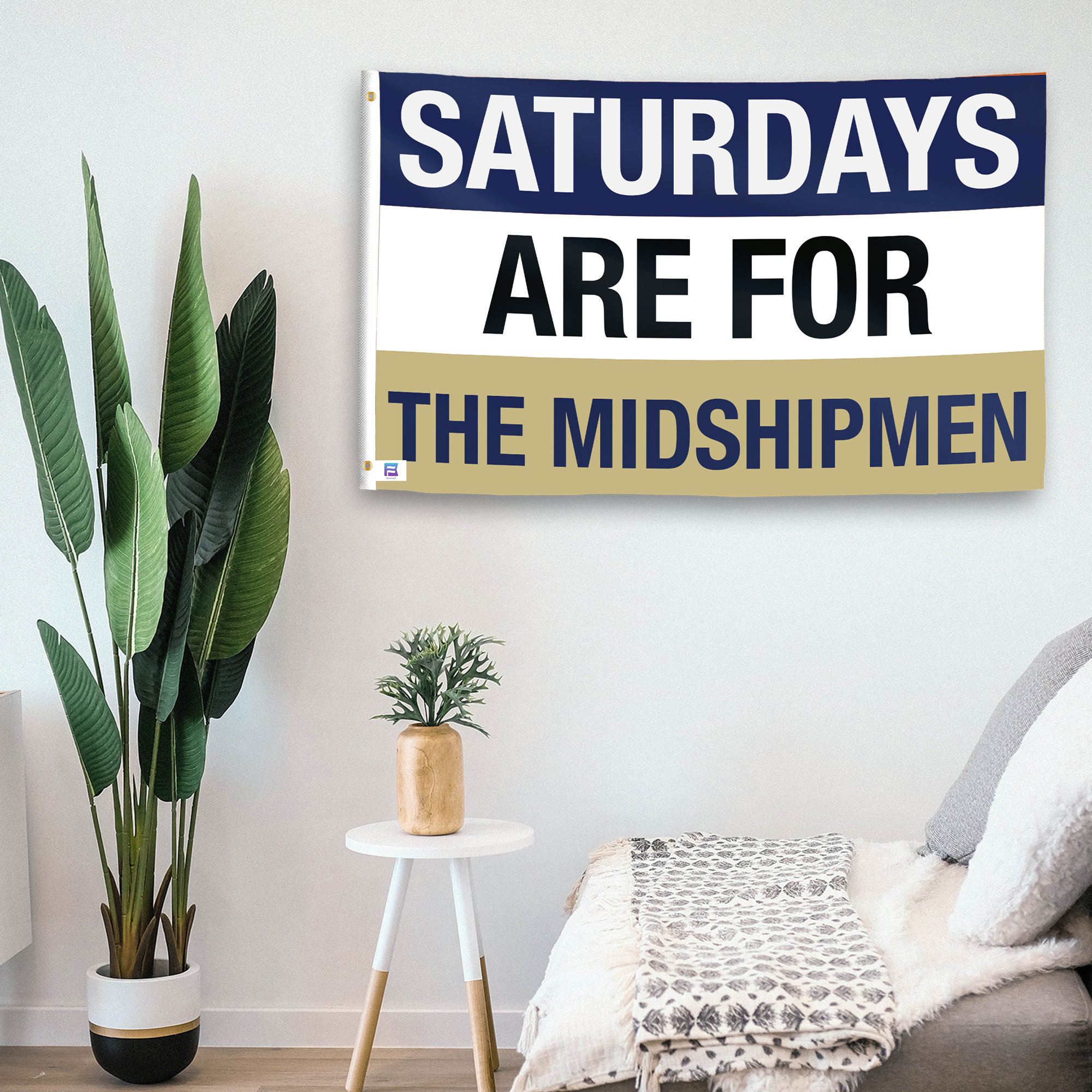 In a home setting, a flag with the saying "Saturdays Are for the Midshipmen" is mounted on a white wall by a side table.