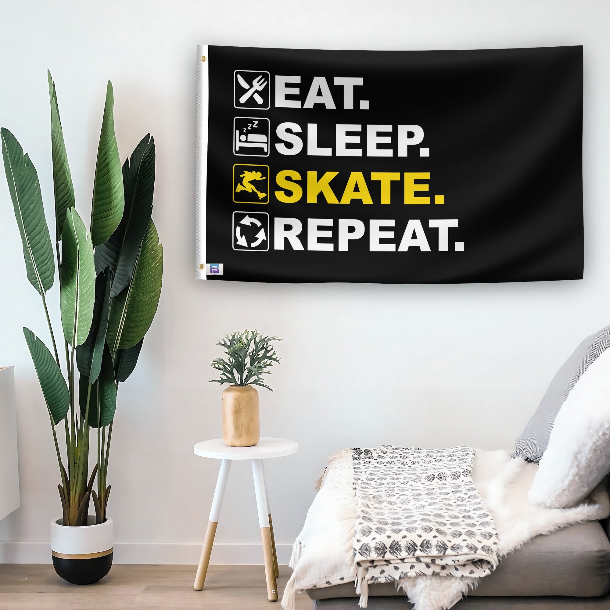 In a home setting, a flag with the saying "Eat Sleep Skate Repeat" is mounted on a white wall by a side table.