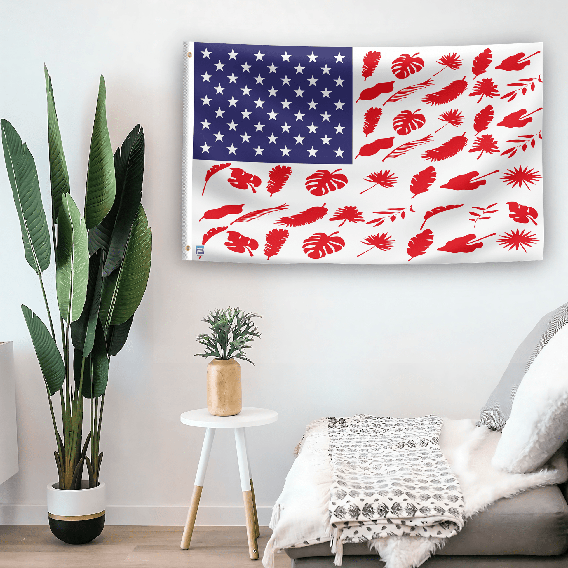 In a home setting, an american flag with the theme "Tree Leaf Stripes American" is mounted on a white wall by a side table.