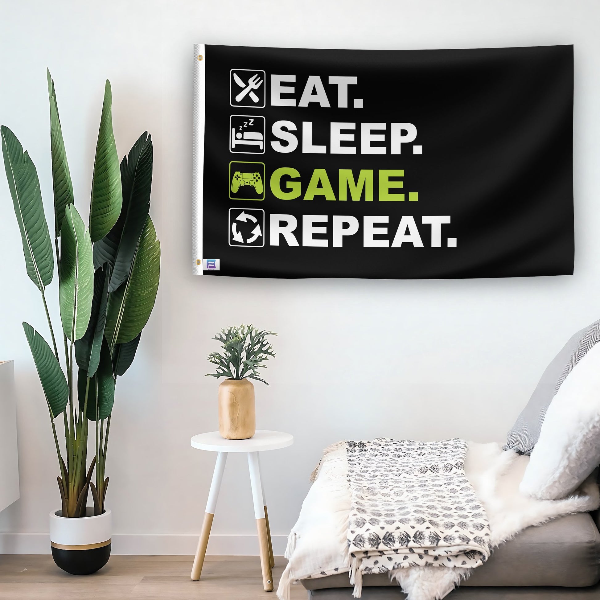 In a home setting, a flag with the saying "Eat Sleep Game Repeat" is mounted on a white wall by a side table.