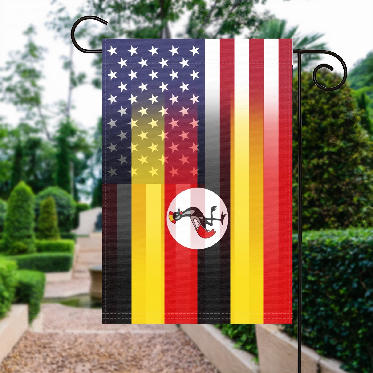 A garden flag with the Ugandan American flag design seamlessly blended with the American flag, displayed in a garden.