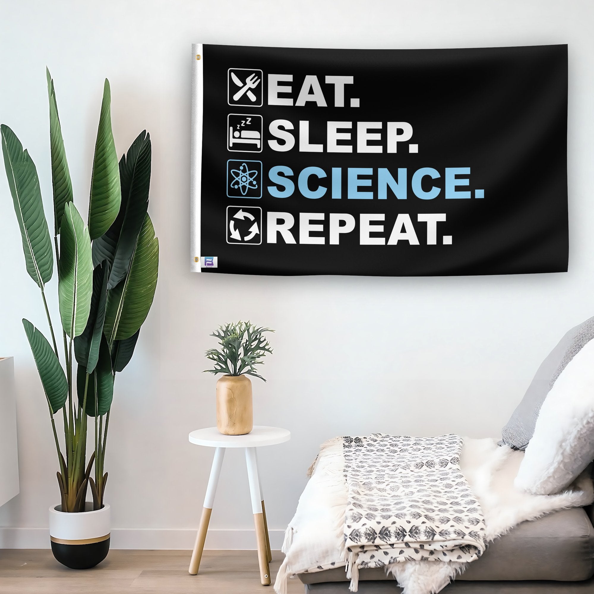 In a home setting, a flag with the saying "Eat Sleep Science Repeat" is mounted on a white wall by a side table.