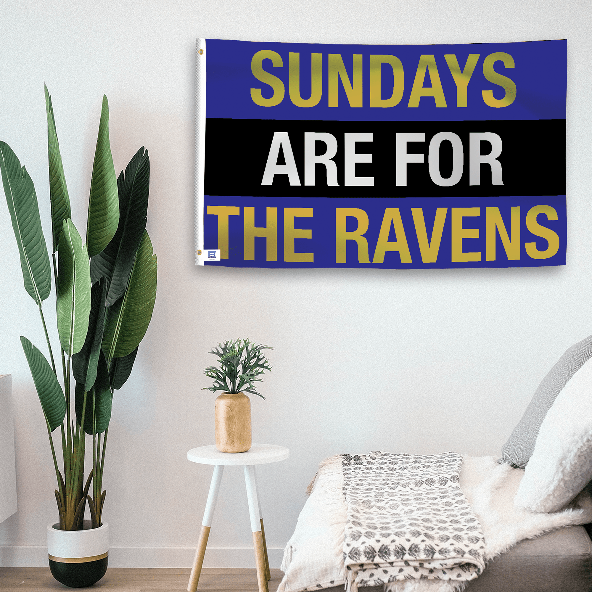 In a home setting, a flag with the saying "https://www.dropbox.com/scl/fi/k9pqfv03gitv3a2nyqb9k/sundays-are-for-the-ravens_room.png?rlkey=tp1287o4uklvvqsb4xlqmk2vc&raw=1" is mounted on a white wall by a side table.