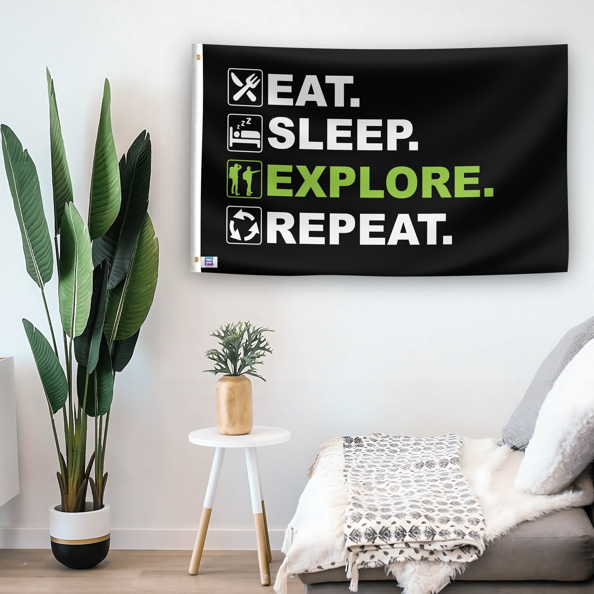 In a home setting, a flag with the saying "Eat Sleep Explore Repeat" is mounted on a white wall by a side table.