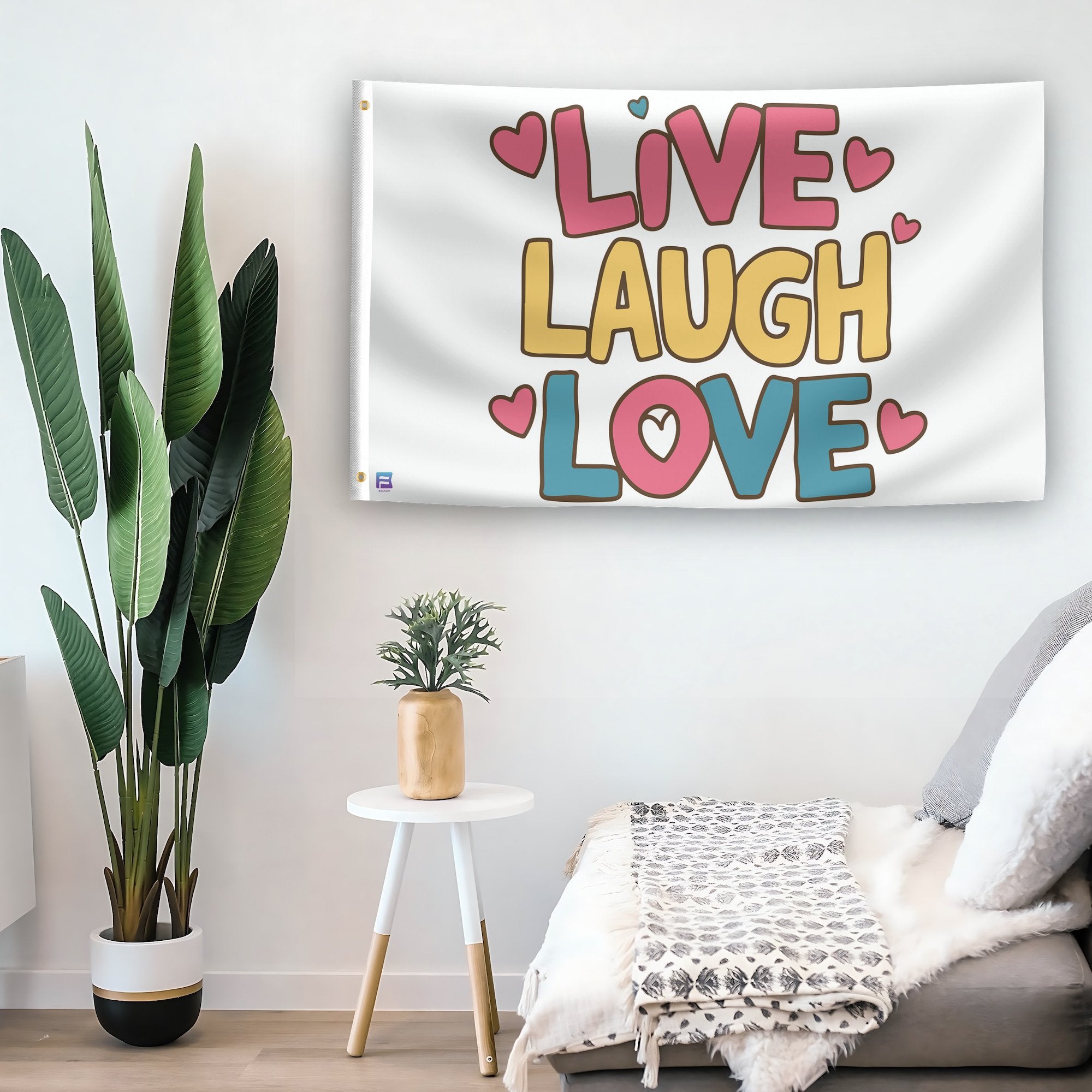 In a home setting, a flag with the saying "Live Laugh Love" is mounted on a white wall by a side table.