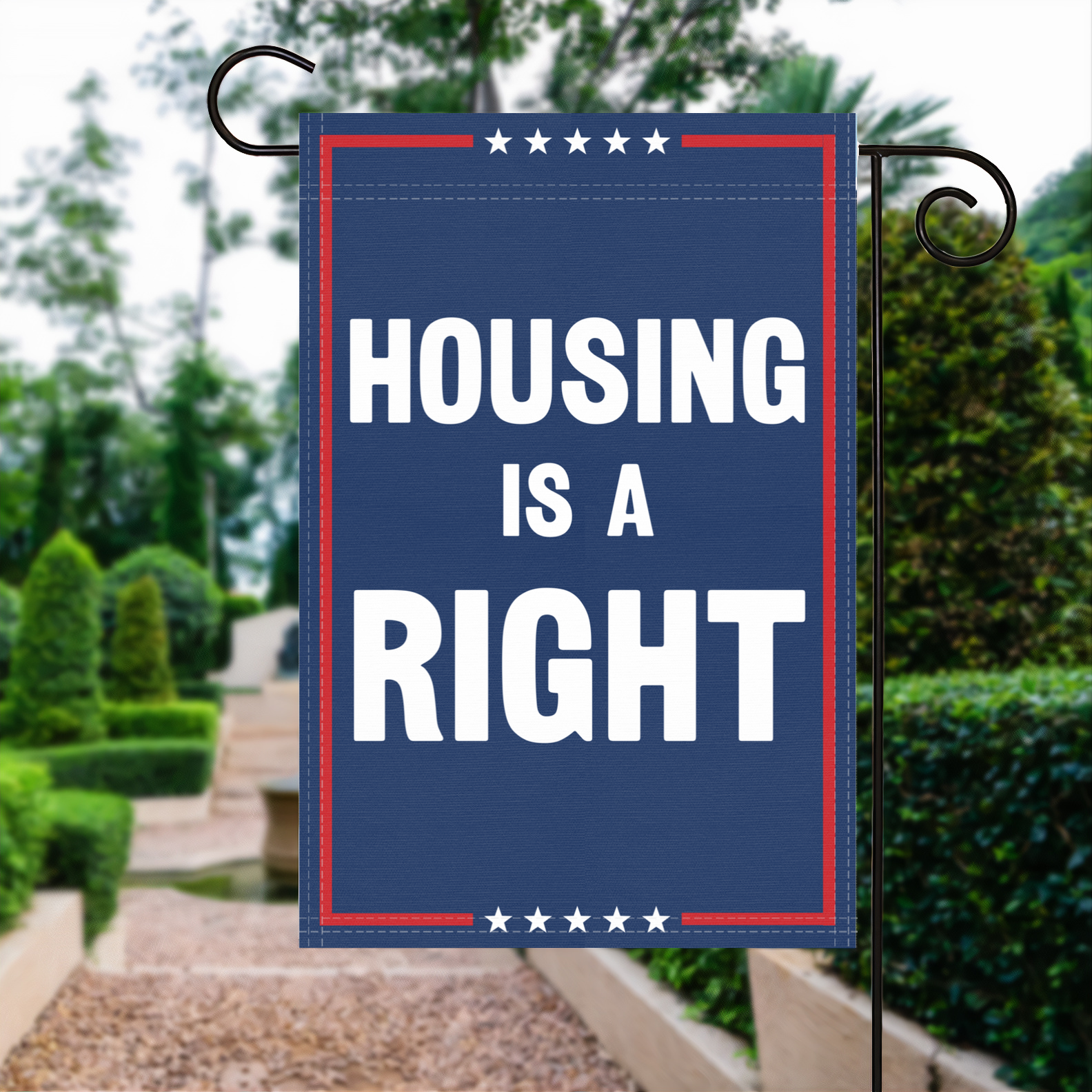 A red, white and blue political garden flag with the slogan Housing Is A Right.