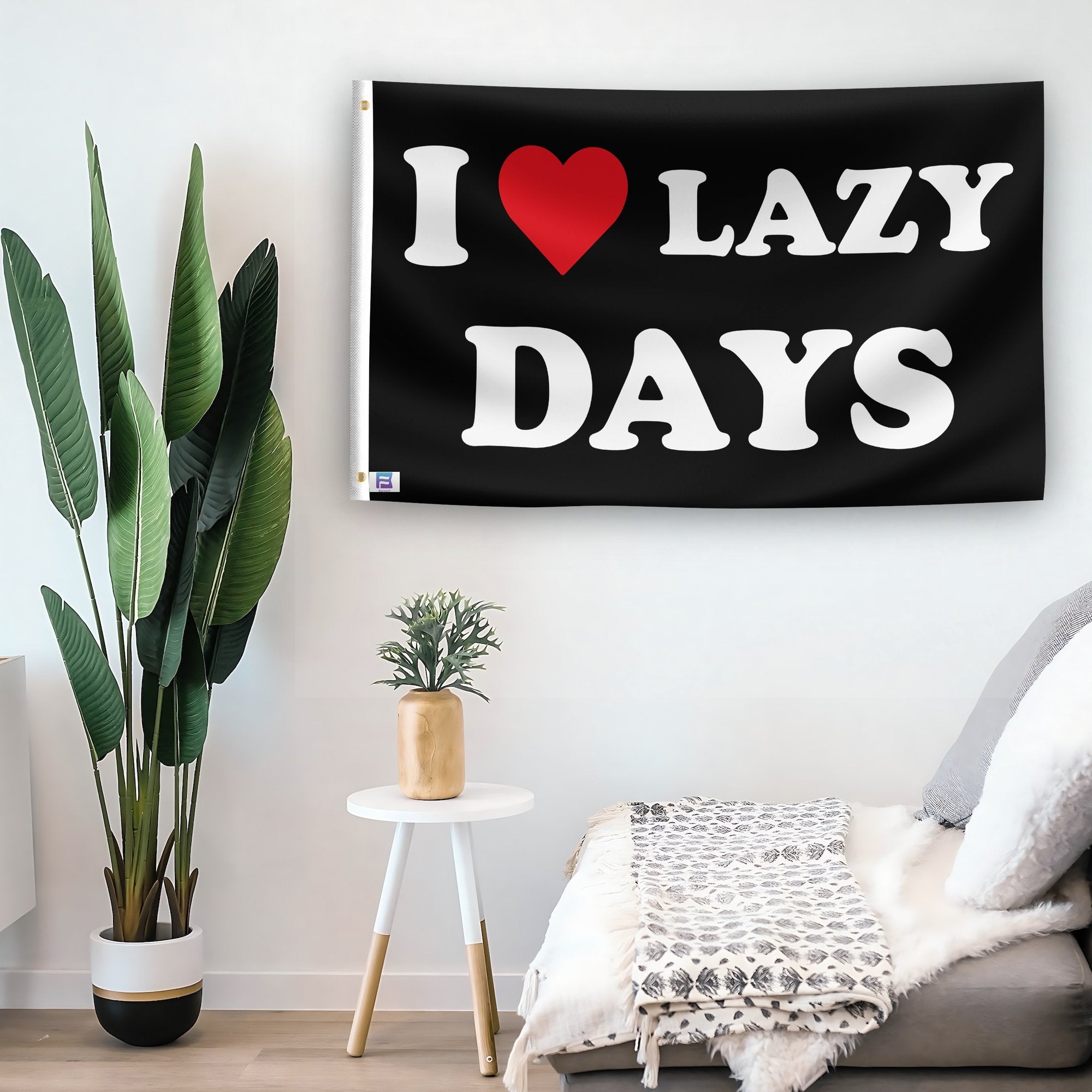 In a home setting, a flag with the saying "I Love Lazy Days" is mounted on a white wall by a side table.